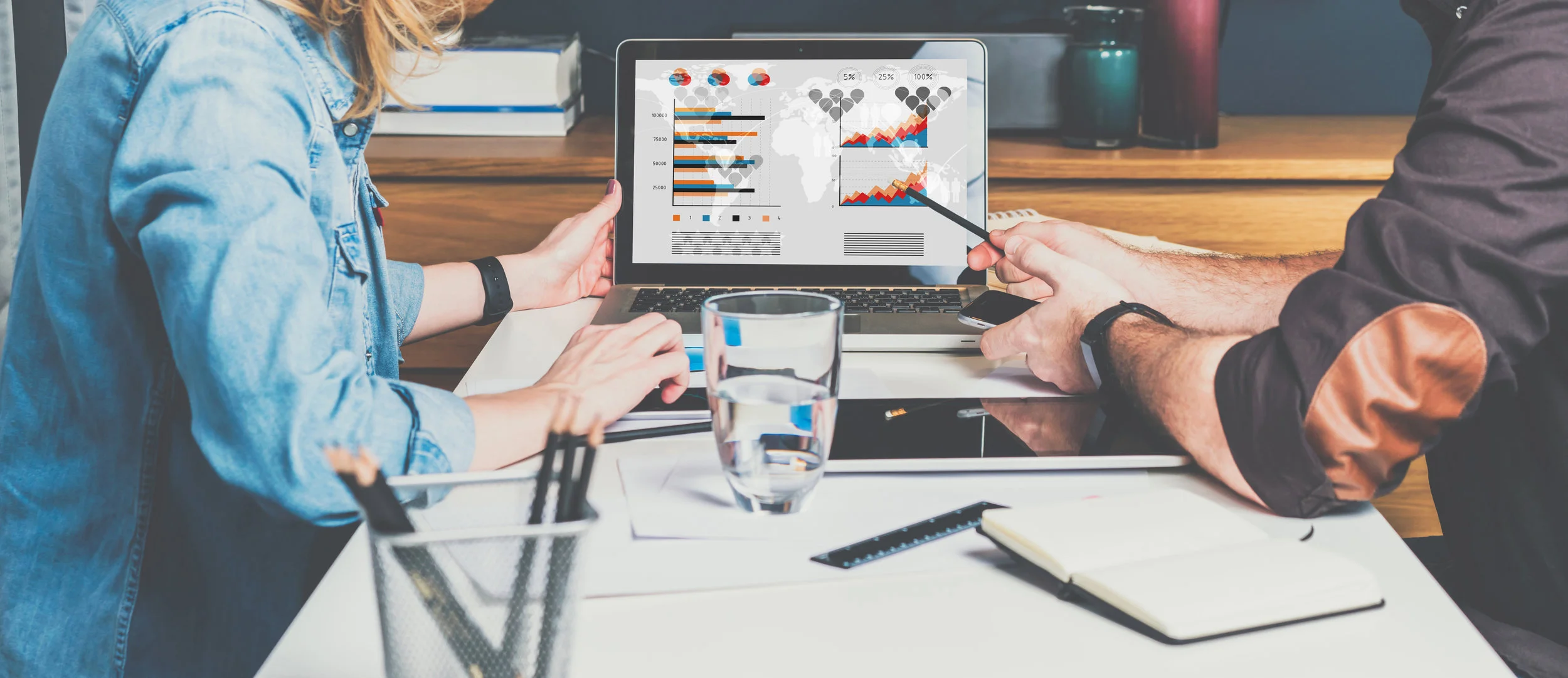 man and woman working on charts on laptop