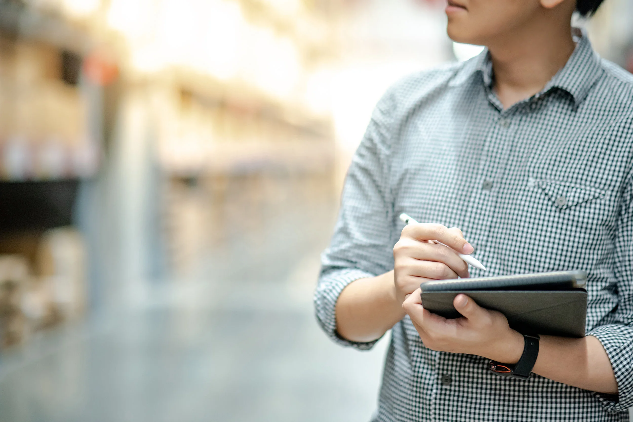 man in checkered shirt holding an ipad and stylus