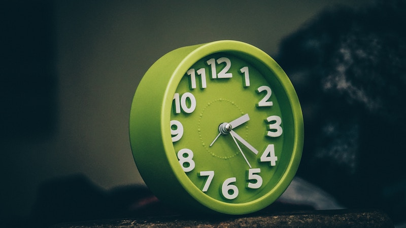 Green clock with white numbers and hands.