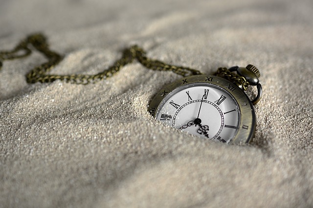 Pocket watch sinking into a pile of sand.