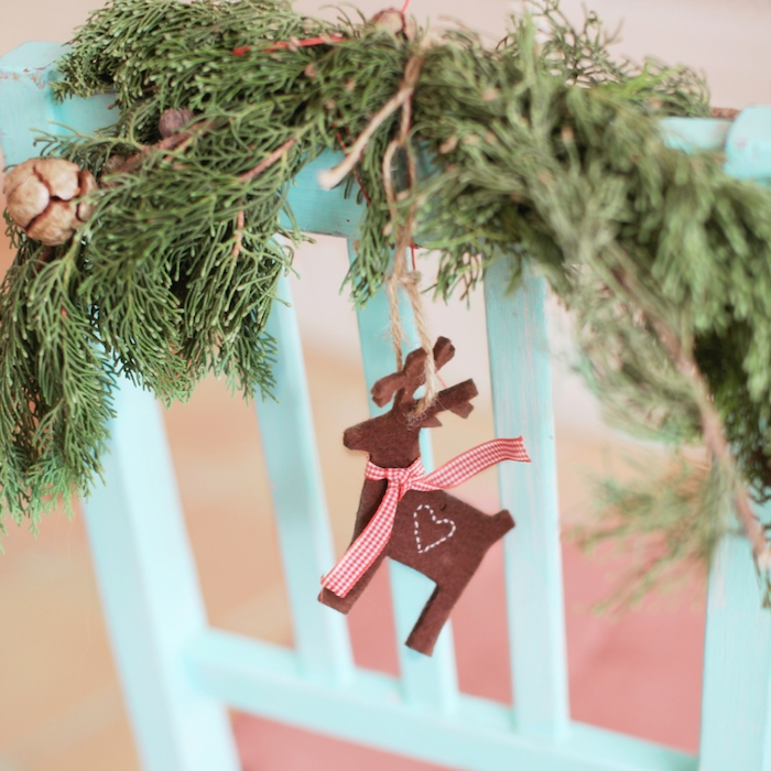Reindeer ornament hanging precariously from a piece of twine wrapped around a holiday wreath.
