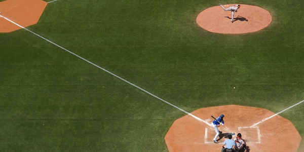 Baseball player throwing a pitch towards the hitter on a baseball field.