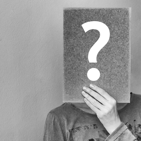 Person holding a question mark in front of their face.