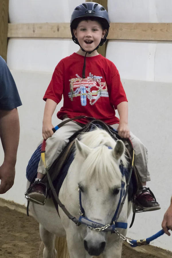 Child riding a TRI therapy horse.