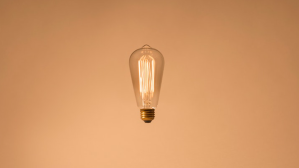 Lightbulb hanging against a blush pink background.