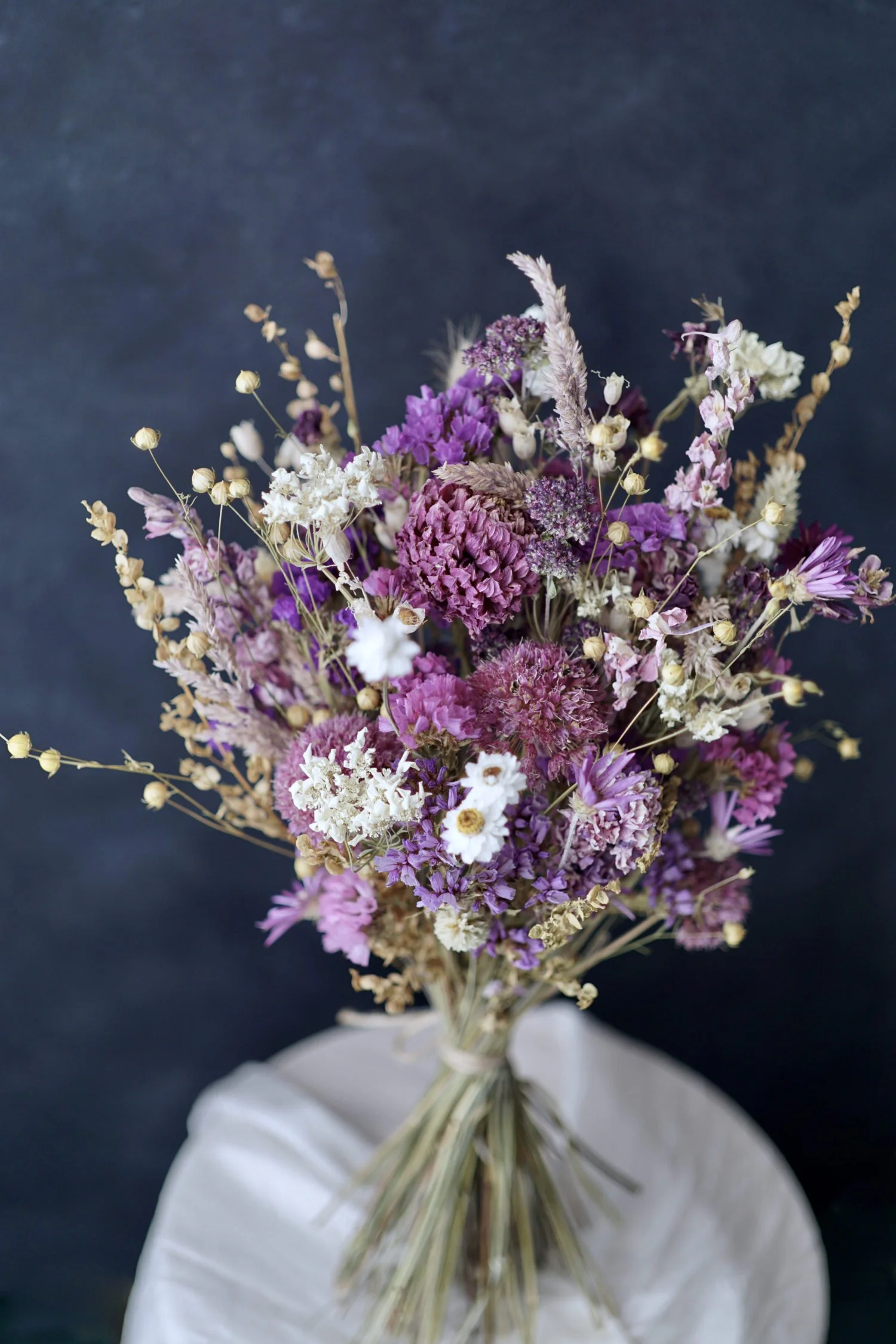 Dried flower bouquet of purple flowers against a dark background.