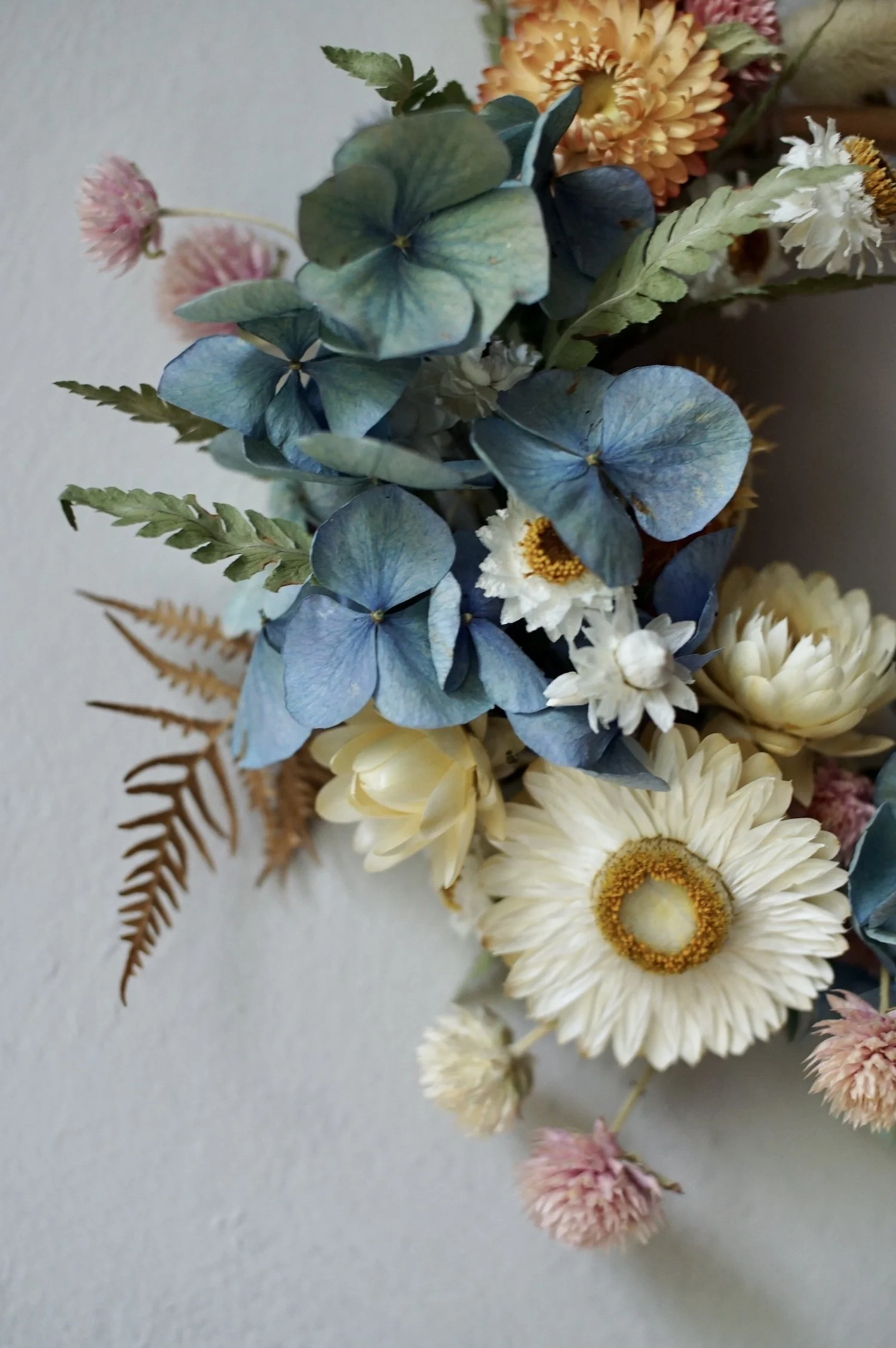 Dried flowers in pastel colours on a mini wreath.