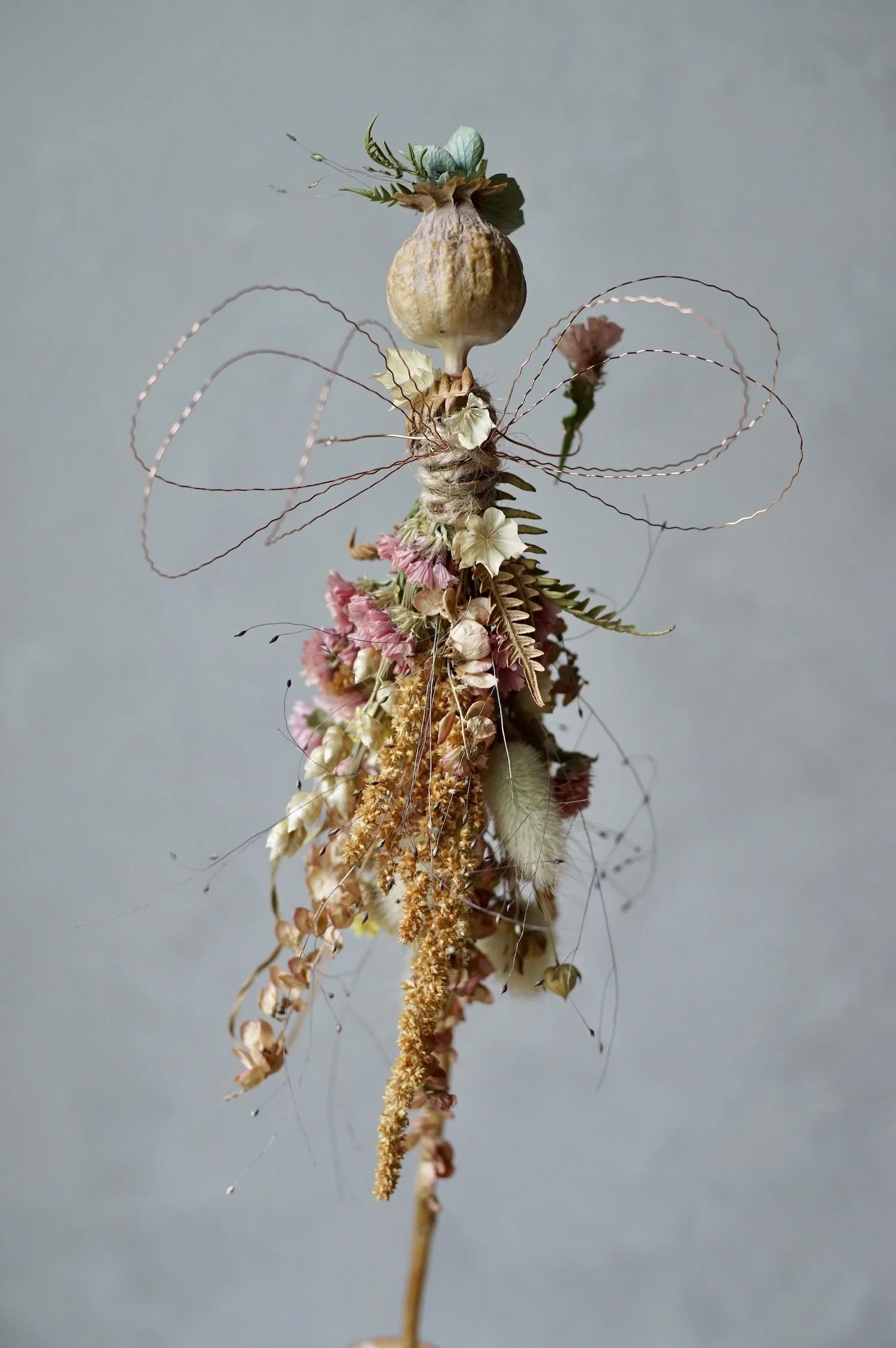 Flower fairy made with a poppy seed head and dried flowers with wire for wings and arms.