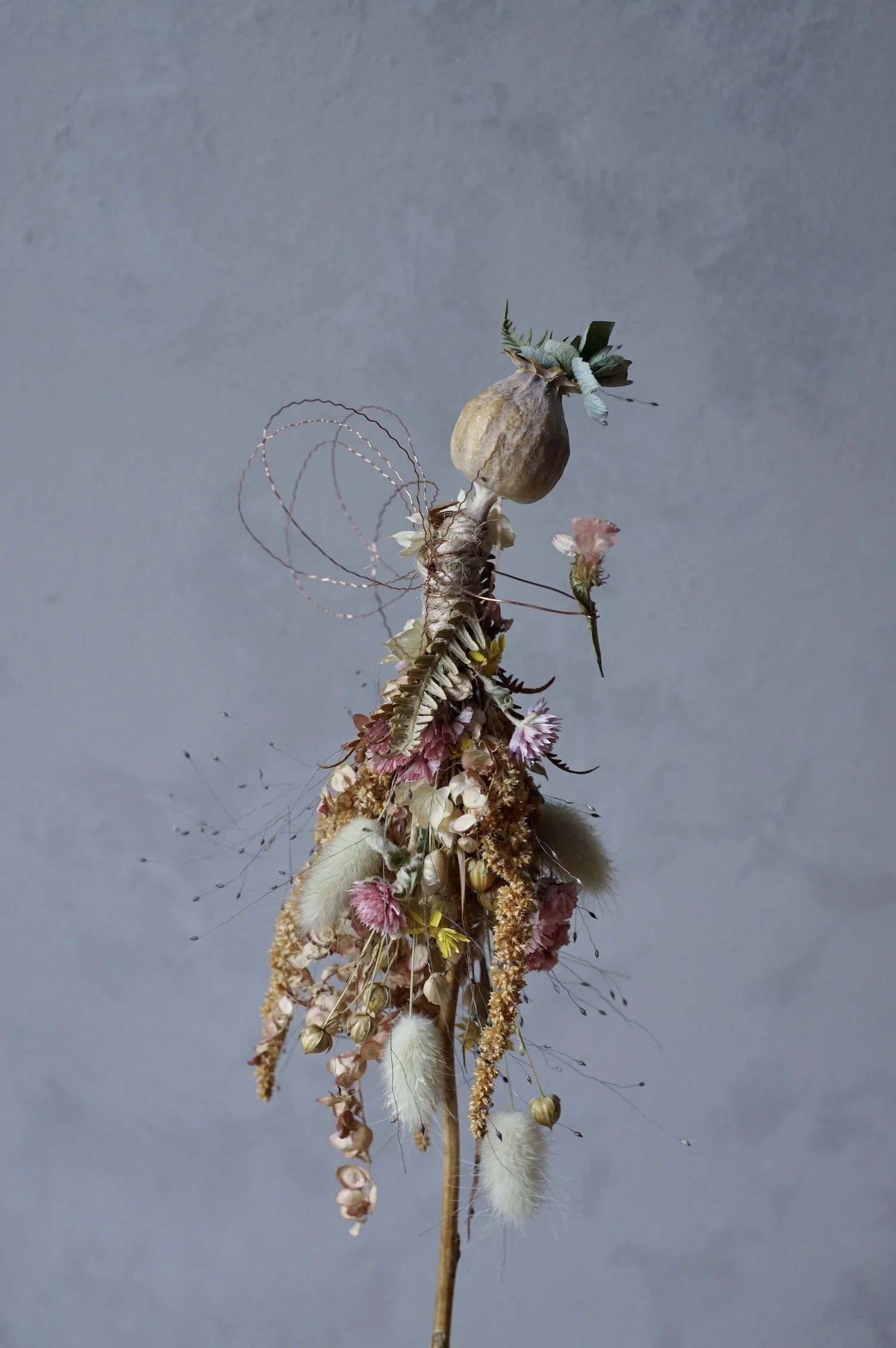 Flower fairy made with a poppy seed head and dried flowers with wire for wings and arms.