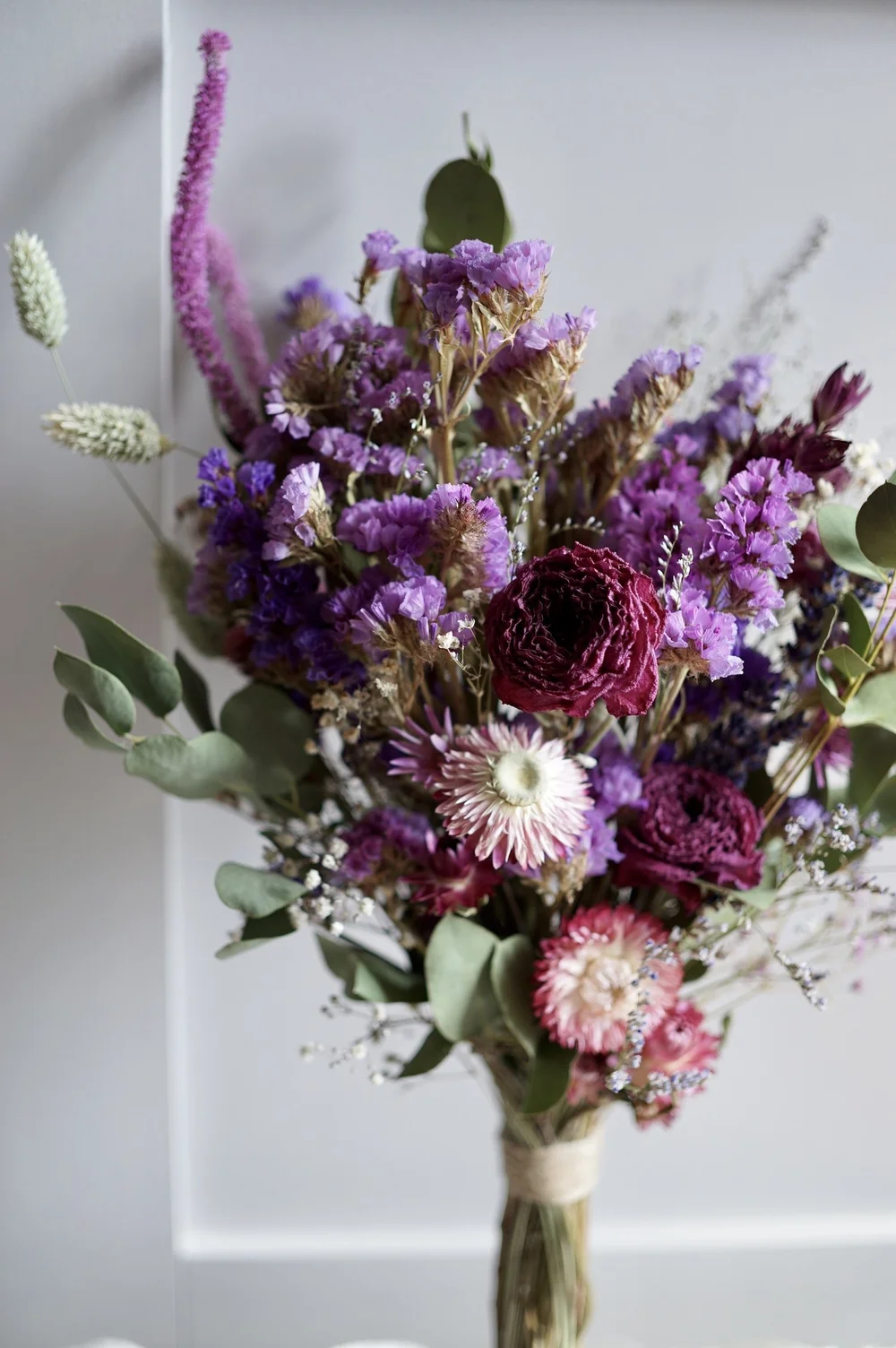 Dried flower bouquet containing purple flowers and green eucalyptus