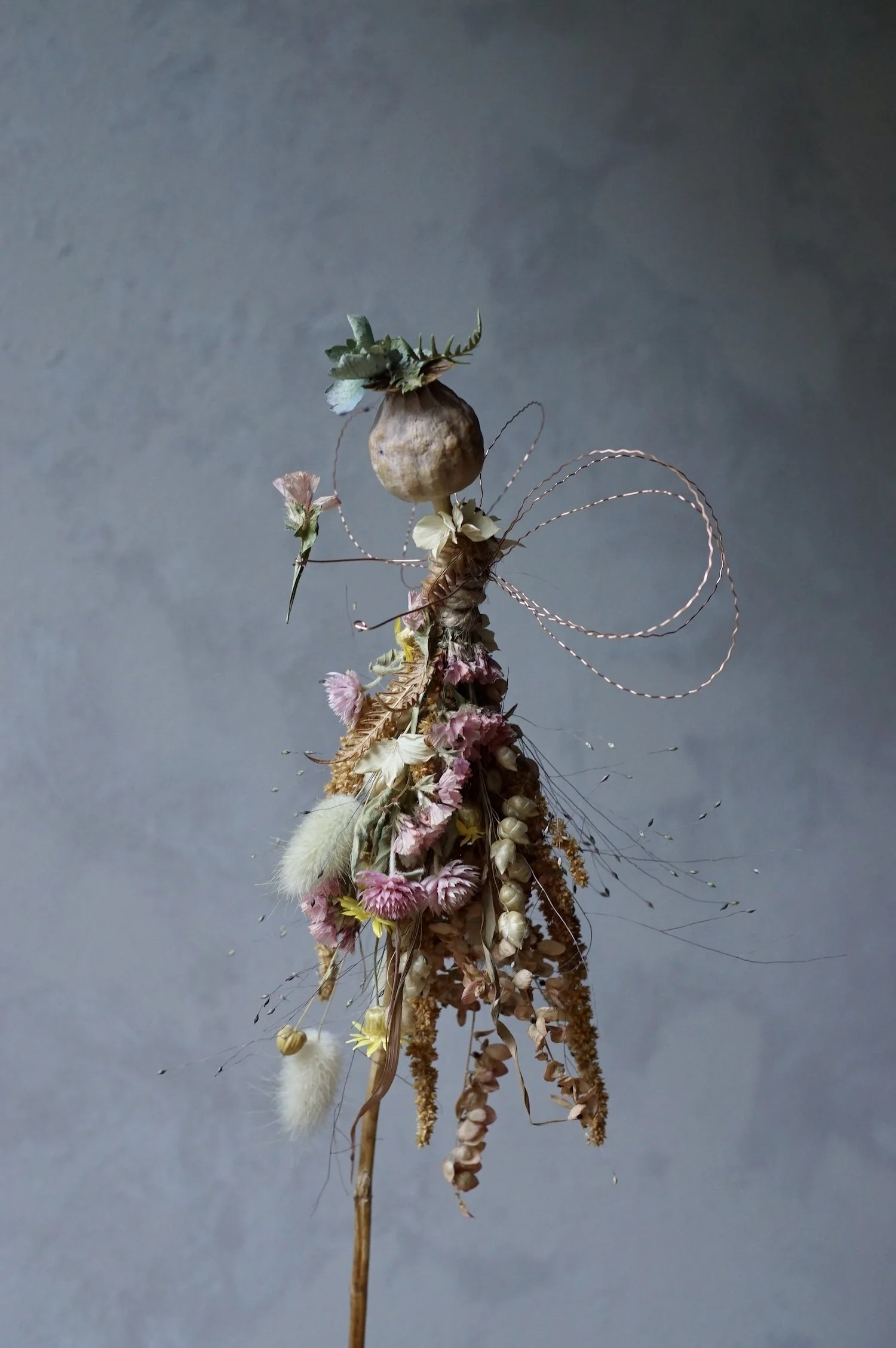 Flower fairy made with a poppy seed head and dried flowers with wire for wings and arms.
