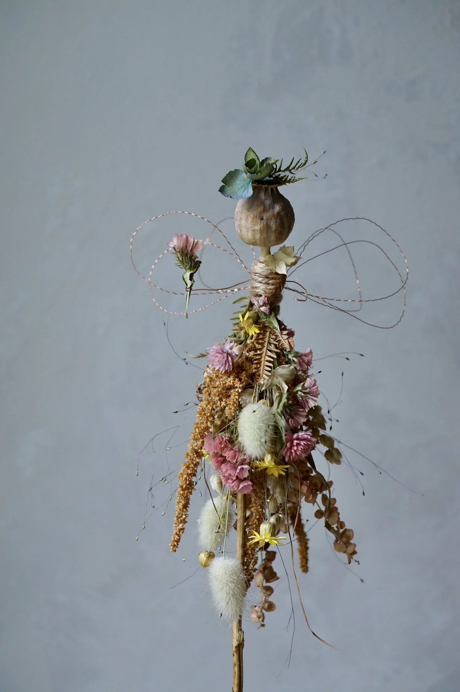 Flower fairy made with a poppy seed head and dried flowers with wire for wings and arms.