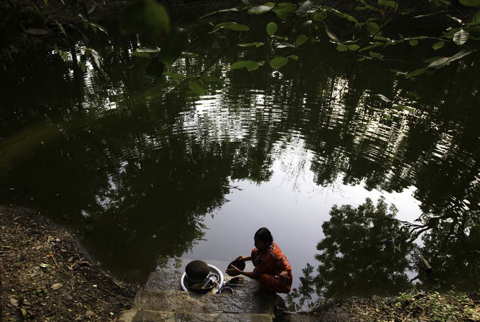  Tohomina Akter washes pots and dishes in a pond near her home in Char Baria, Barisal, Bangladesh. 