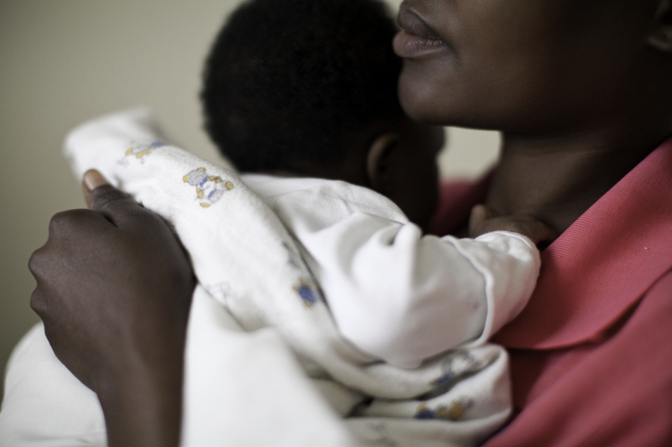  A mother holds her child while listening to Juliette Mukayinga, a research nurse for the Kabeho study, as she asks questions at the Remera Health Center in Kigali, Rwanda. Mothers meet with their respective study nurses once a month to answer a seri