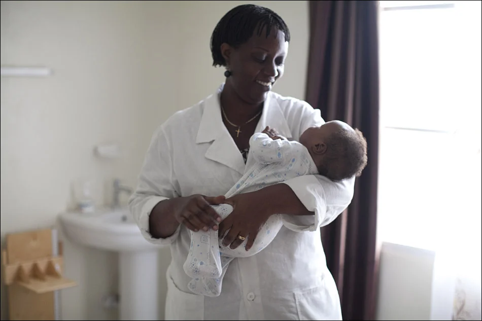 Juliette Mukayinga, a research nurse, holds a baby after examining the child as part of the Elizabeth Glaser Pediatric AIDS Foundation’s research into the impact of nutrition on preventing mother-to-child transmission of HIV, the virus that causes AIDS. © Laura Elizabeth Pohl
