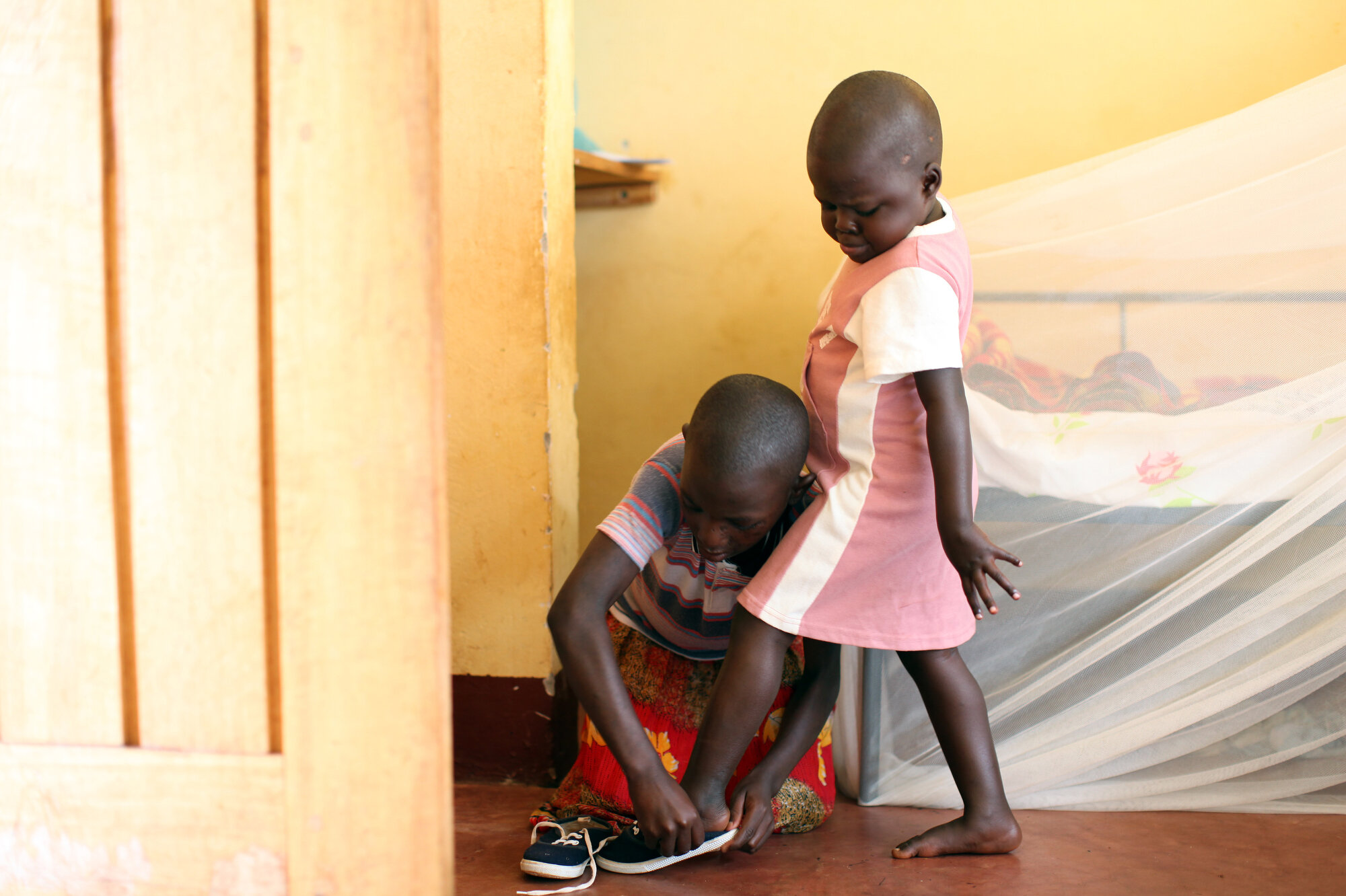  Helen helps Desire put on her shoes at Omoana House, a residential rehabilitation center for malnourished children in Njeru, Uganda. The older kids pitch in with caring for the younger kids, often treating them like siblings. Once the children are r