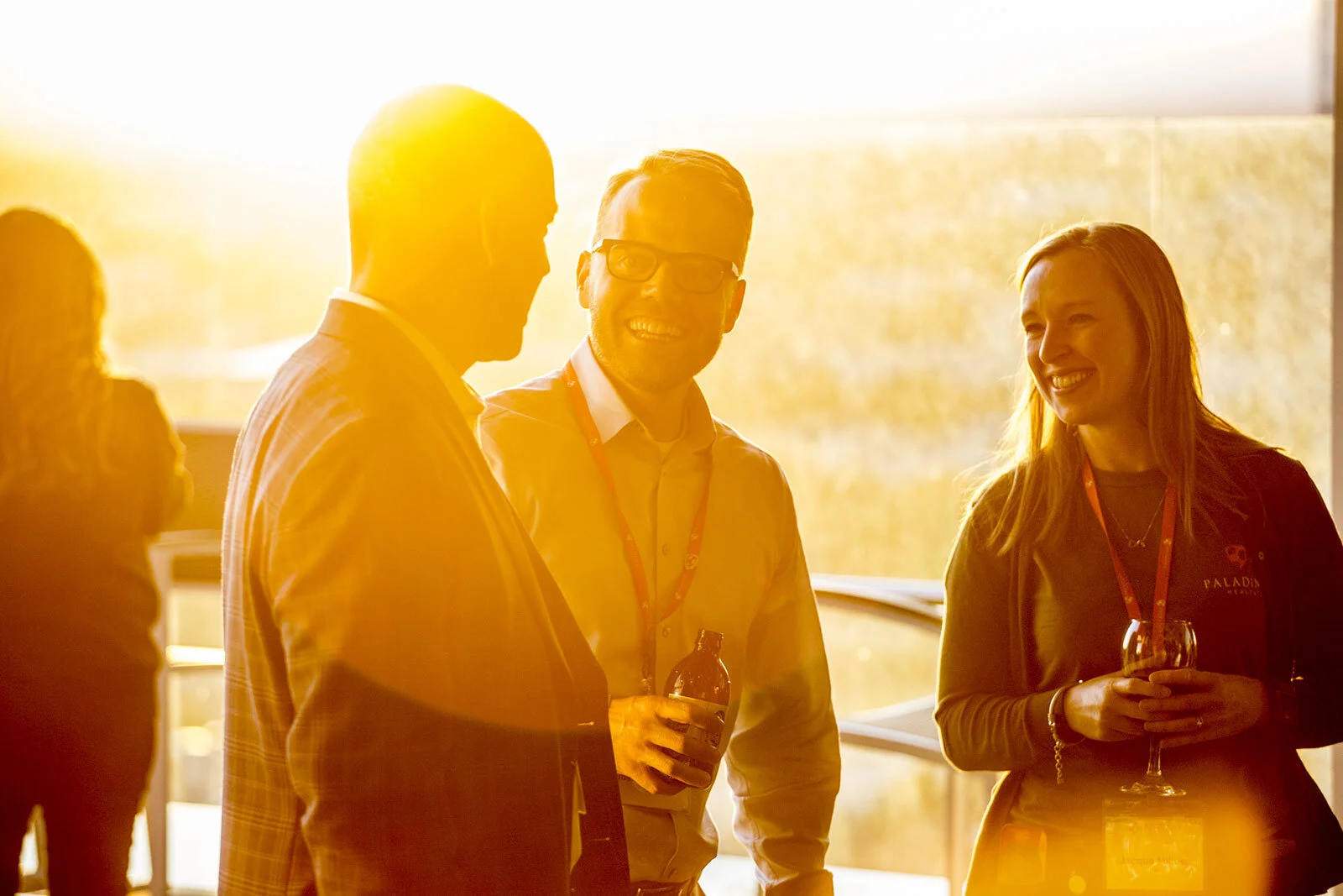 Colorado-based photographer Nathan W. Armes captures a vibrant, backlit moment of three conference attendees enjoying a conversation during sunset, with warm golden hues illuminating the scene.