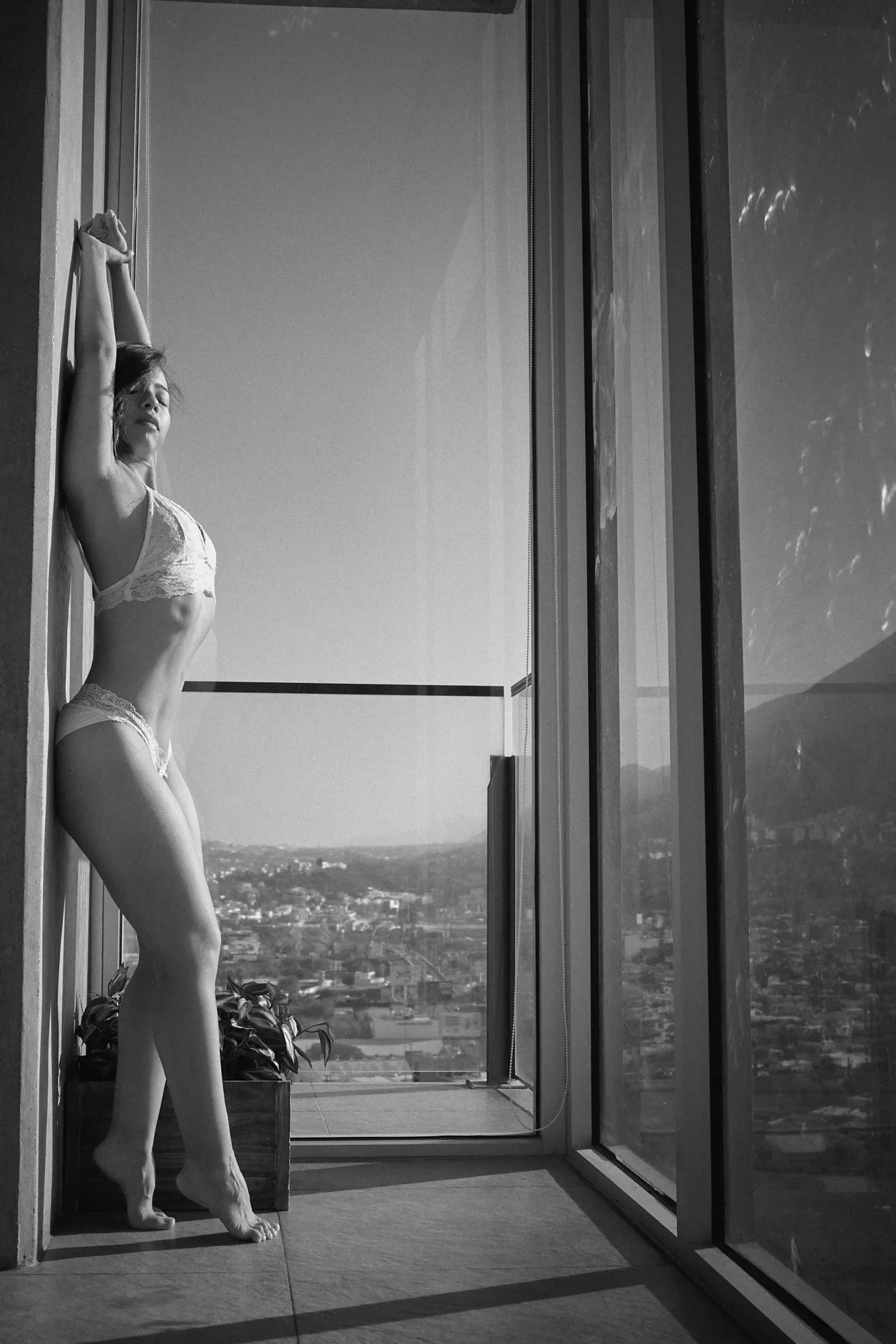 Mujer en lencería durante una sesión boudoir en blanco y negro junto a una ventana en Monterrey