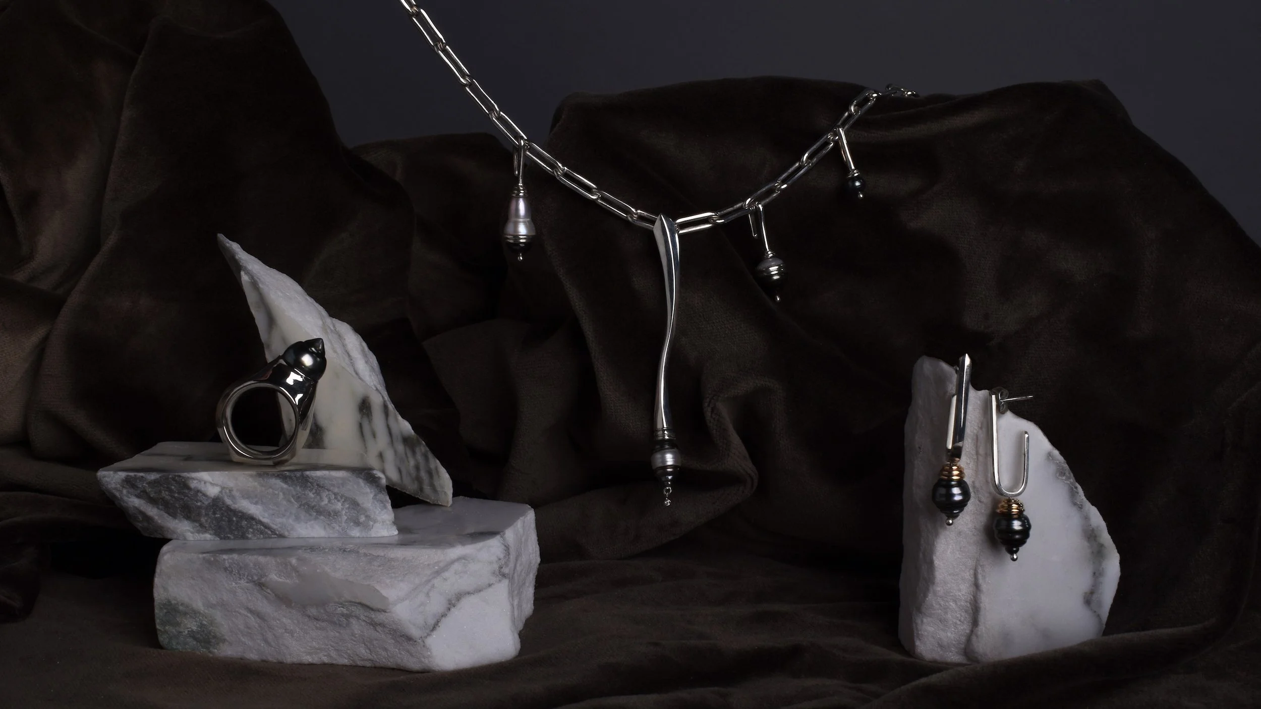 still life of Ebb&Flow collection statement Spindrift mixed Pearl necklace, Spinning Tahitian Pearl Shore ring and silver, dark pearl and gold Eddy Earrings