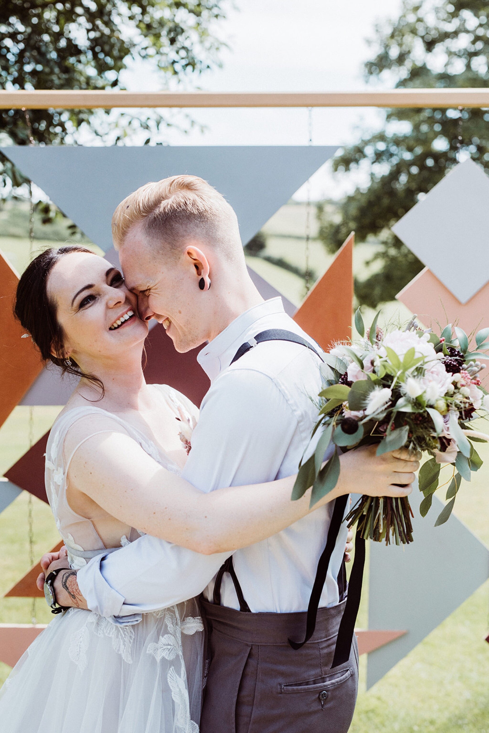 19_V+D Wedding-391_Close up of Bride and groom kissing in front of geometric wedding arch Summer outdoor humanist wedding ceremony..jpg
