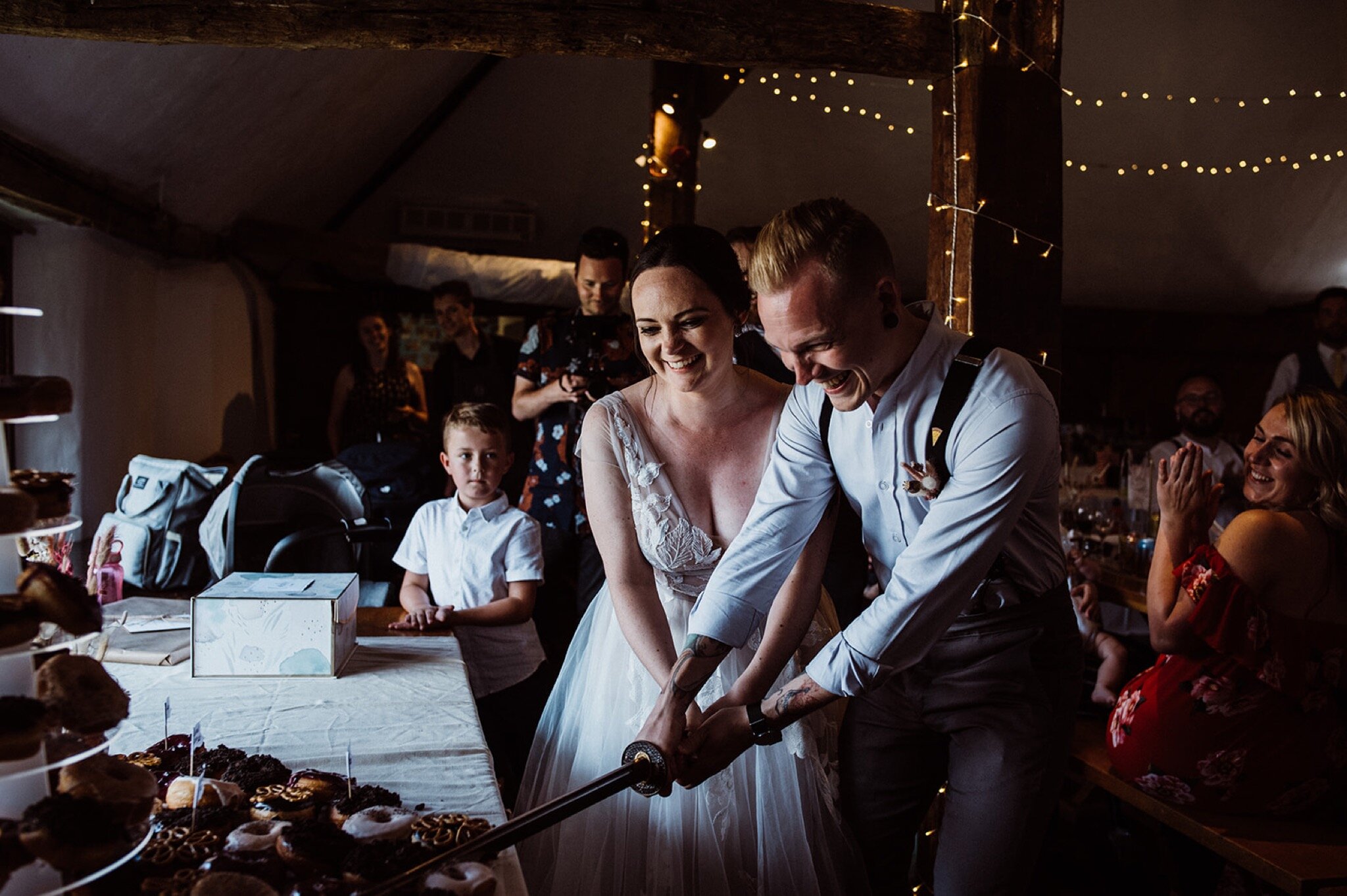 38_V+D Wedding-627_bride and groom using sword to cut a donut%0A.jpg