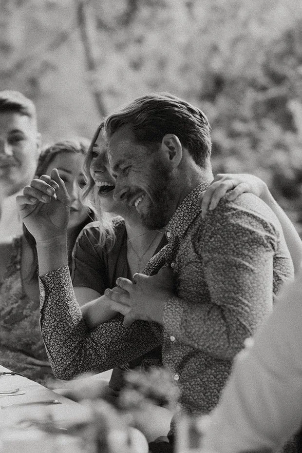Candid black and white photo of a guest laughing during the wedding reception.