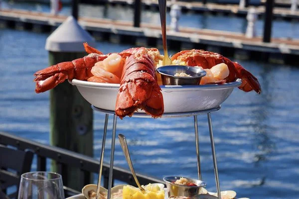 Lobster and seafood platter served on a tiered stand by the water.