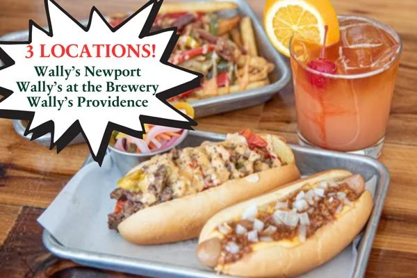 Tray with two hot dogs topped with chili, and an assortment of salads, with a glass of pink lemonade garnished with a lemon wedge and cherry on a wooden table.