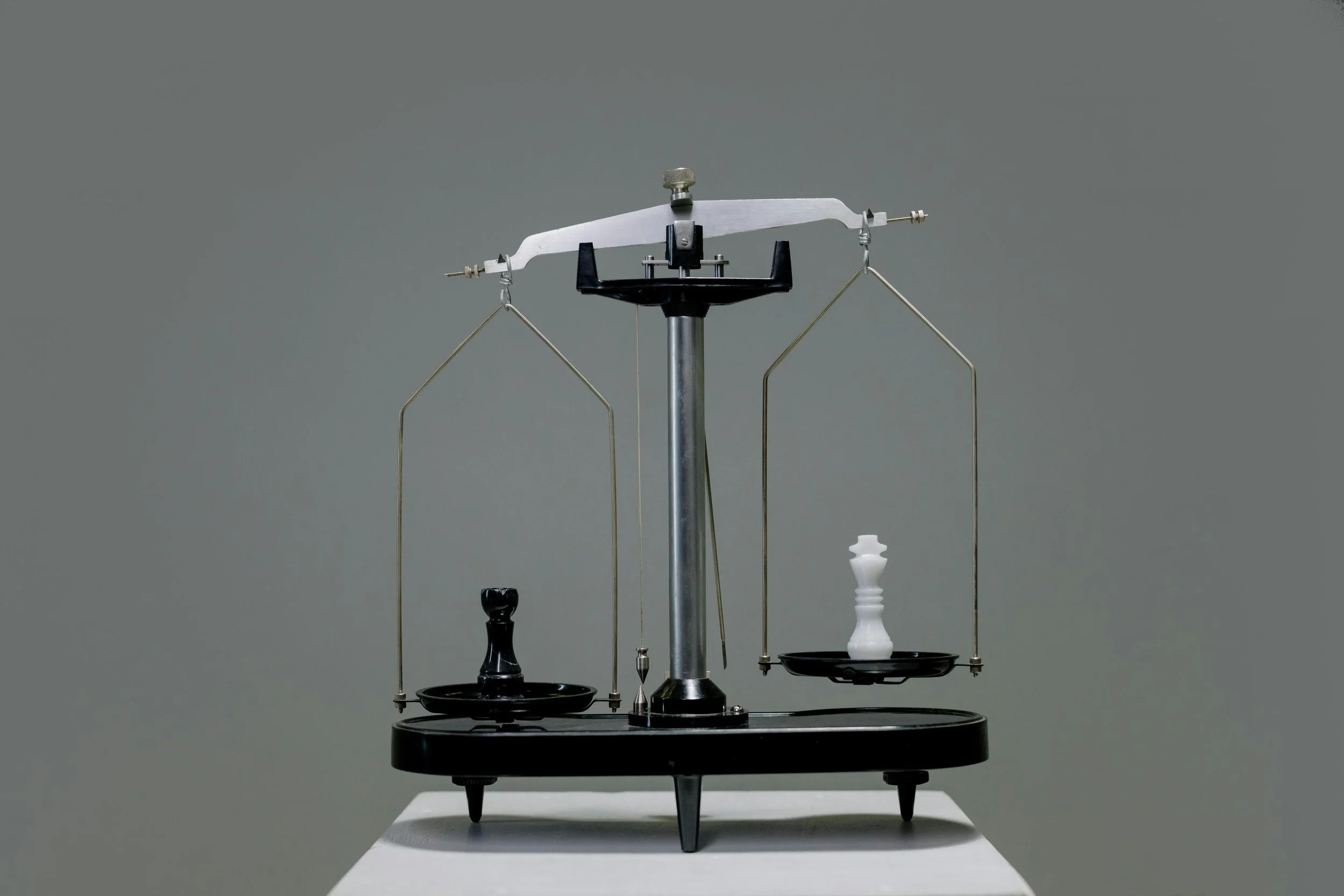 An old fashioned balance holding a chess piece on each side
