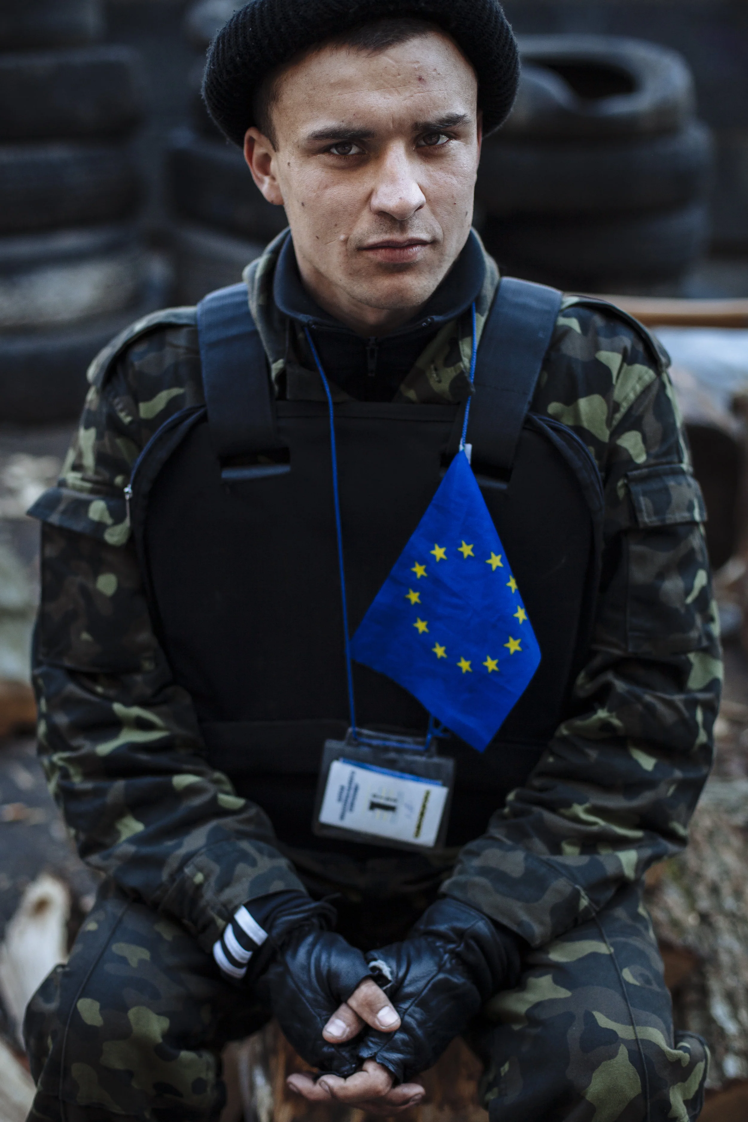 A self defense volunteer with a European Union flag affixed to his protective vest guards a barricade in Kiev's Independence Square, Ukraine, Tuesday, March 11, 2014. (AP Photo/David Azia)