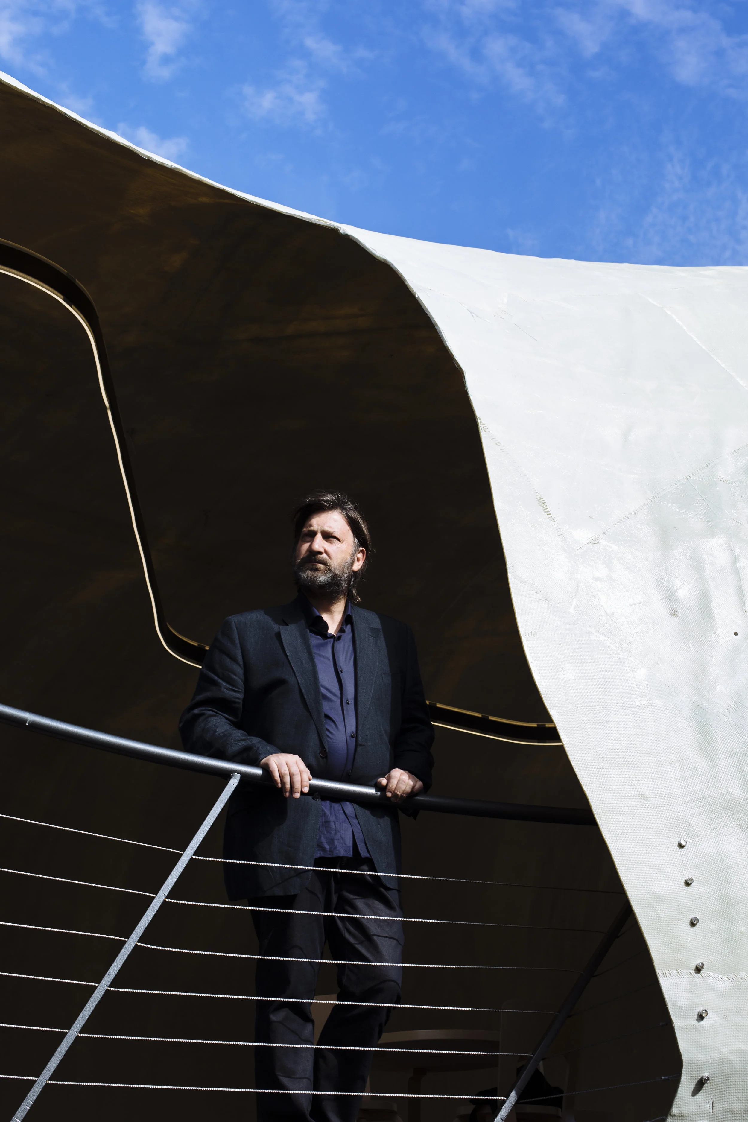 Chilean architect Smiljan Radić poses for a photograph inside the pavilion he designed for the Serpentine Gallery in Kensington Gardens, central London, Friday, July 4, 2014. (David Azia for The New York Times)