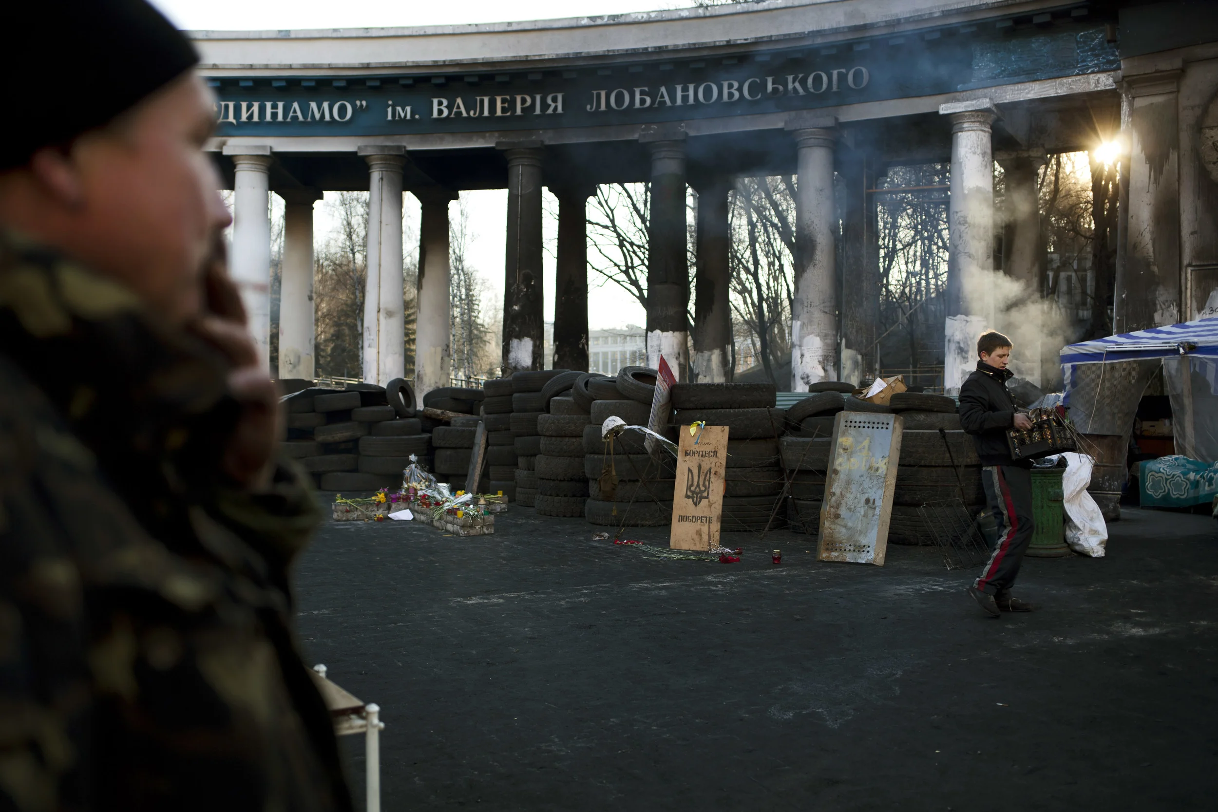 A man, at right, clears bottles at a barricade near the entrance to the stadium of Dynamo Kyiv soccer club in Kiev, Ukraine, Wednesday, March 12, 2014. Ukraine's domestic soccer league will resume play on March 15, after a two-week postponement because of the turmoil in the country. (AP Photo/David Azia)