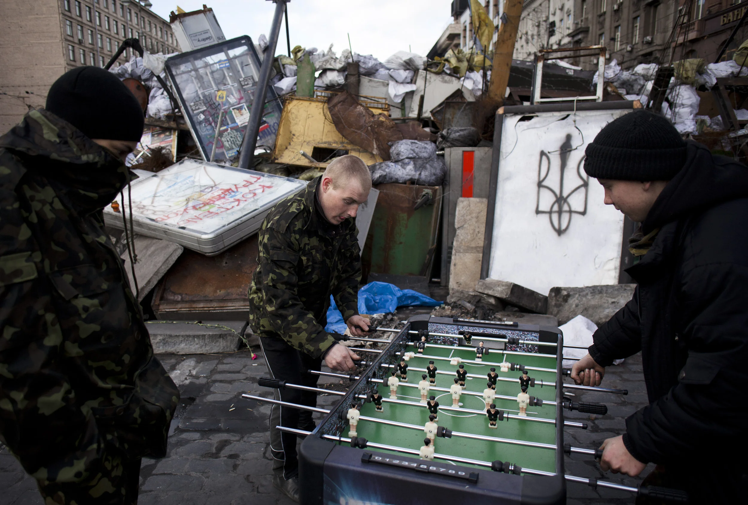 Youths, who are members of a self defense volunteer group, play table football next to a barricade on a road leading to Kiev's Independence Square, Ukraine, Sunday, March 16, 2014. Residents of Ukraine's Crimea region are voting on Sunday in a contentious referendum on whether to split off and seek annexation by Russia. (AP Photo/David Azia)