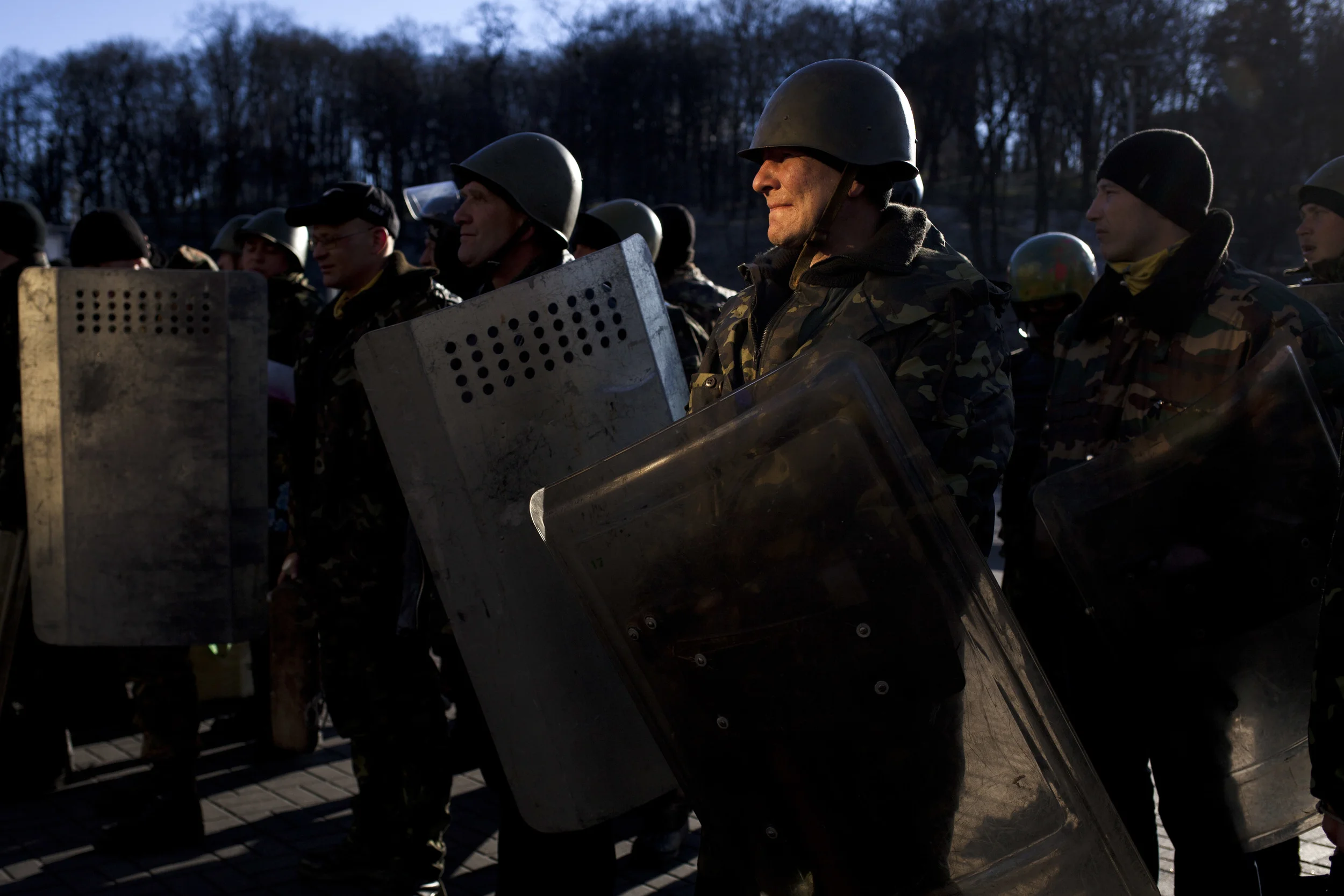 A member of a self defense volunteer group is illuminated by light reflected in a nearby building as he and others line up before marching to the Parliament in Kiev, Ukraine, Monday, March 17, 2014. A referendum held in Crimea on Sunday was widely condemned by Western leaders who were planning to discuss economic sanctions to punish Russia on Monday. Ukraine's new government in Kiev called the referendum a "circus" directed at gunpoint by Moscow.(AP Photo/David Azia)