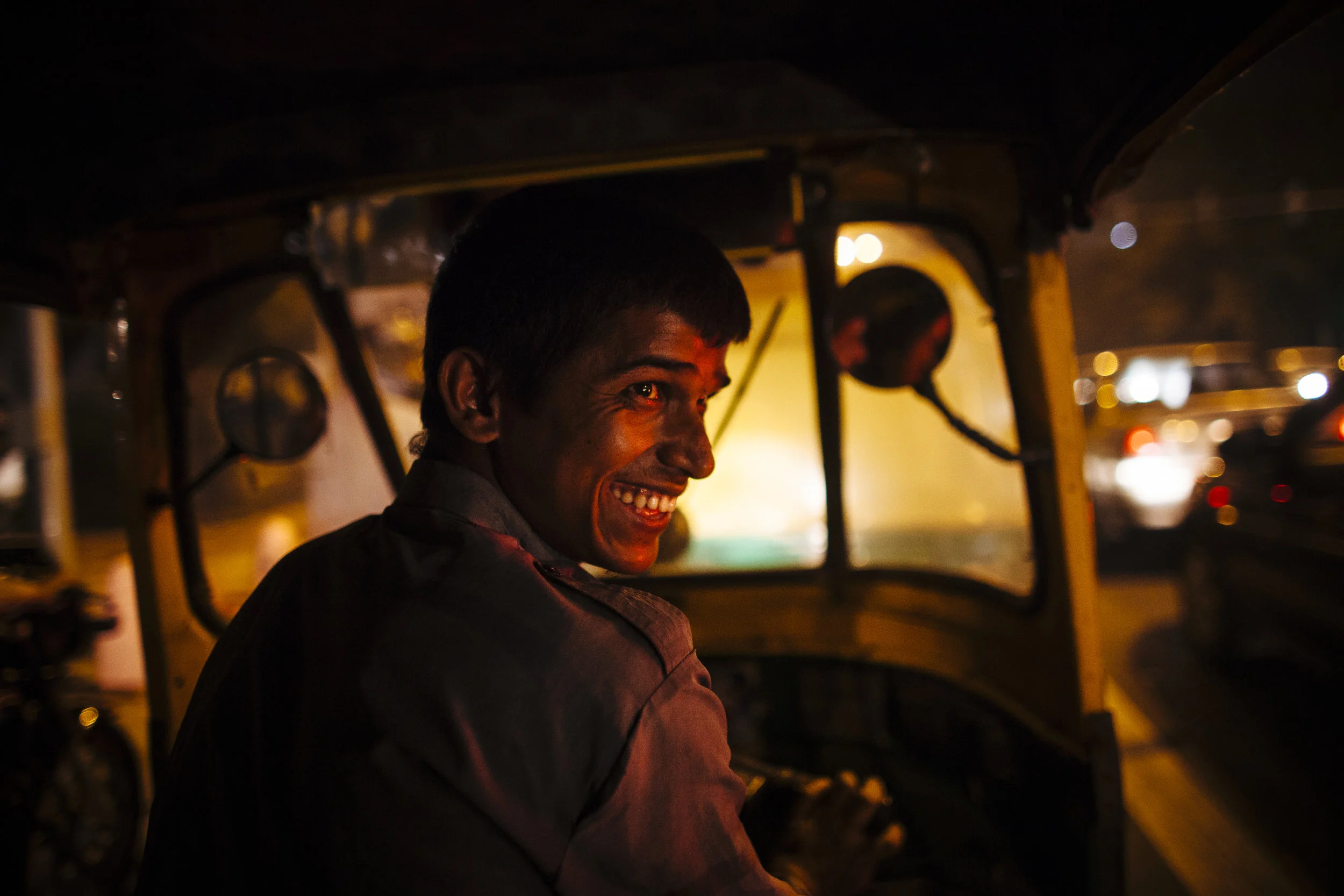 An auto-rickshaw drive smiles as he negotiates evening traffic during the Commonwealth Games in New Delhi, India, Wednesday, Oct. 6, 2010.