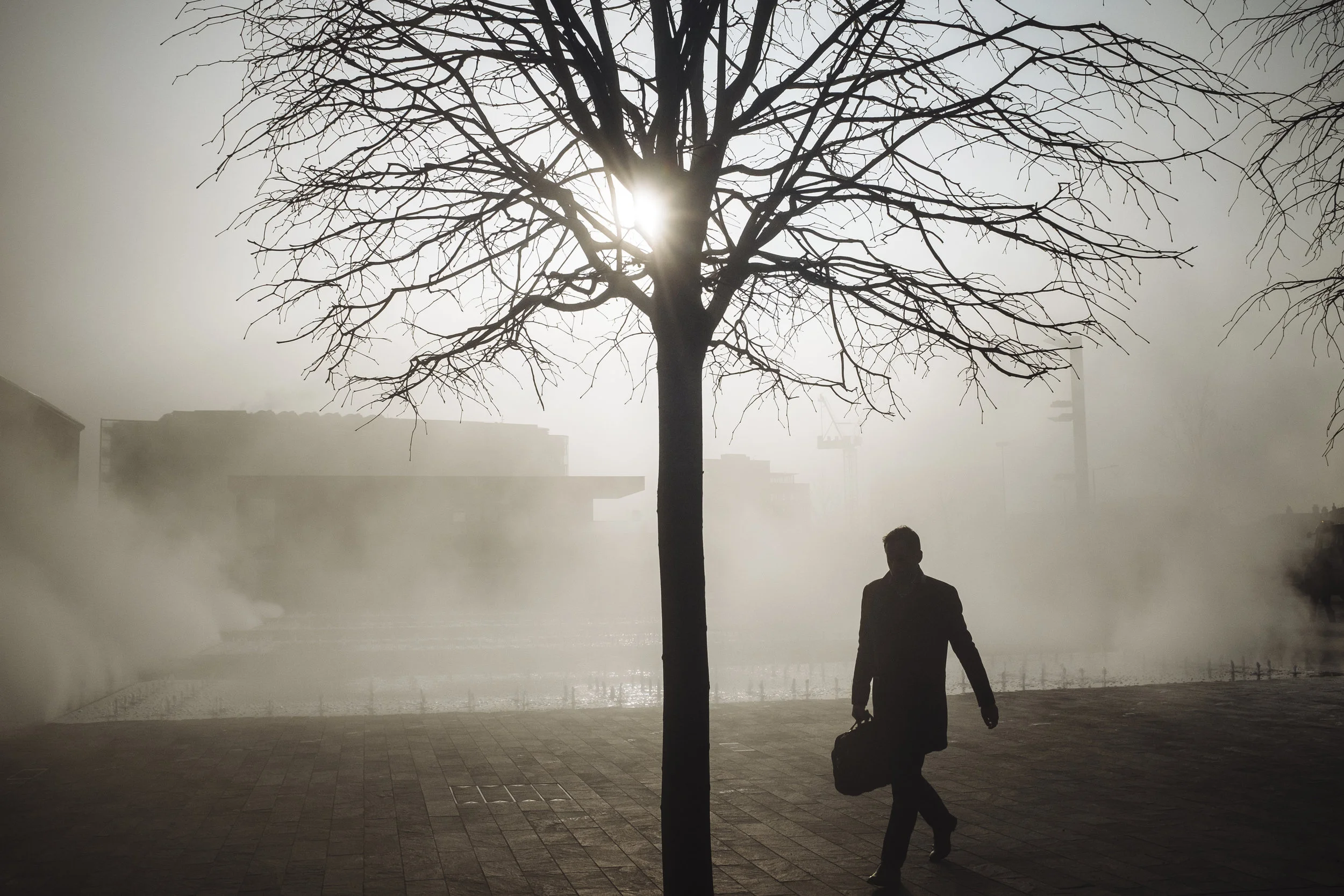 A pedestrian walks through steam rising from the fountains on Granary Square, King's Cross, London, England, Friday, March 11, 2016.