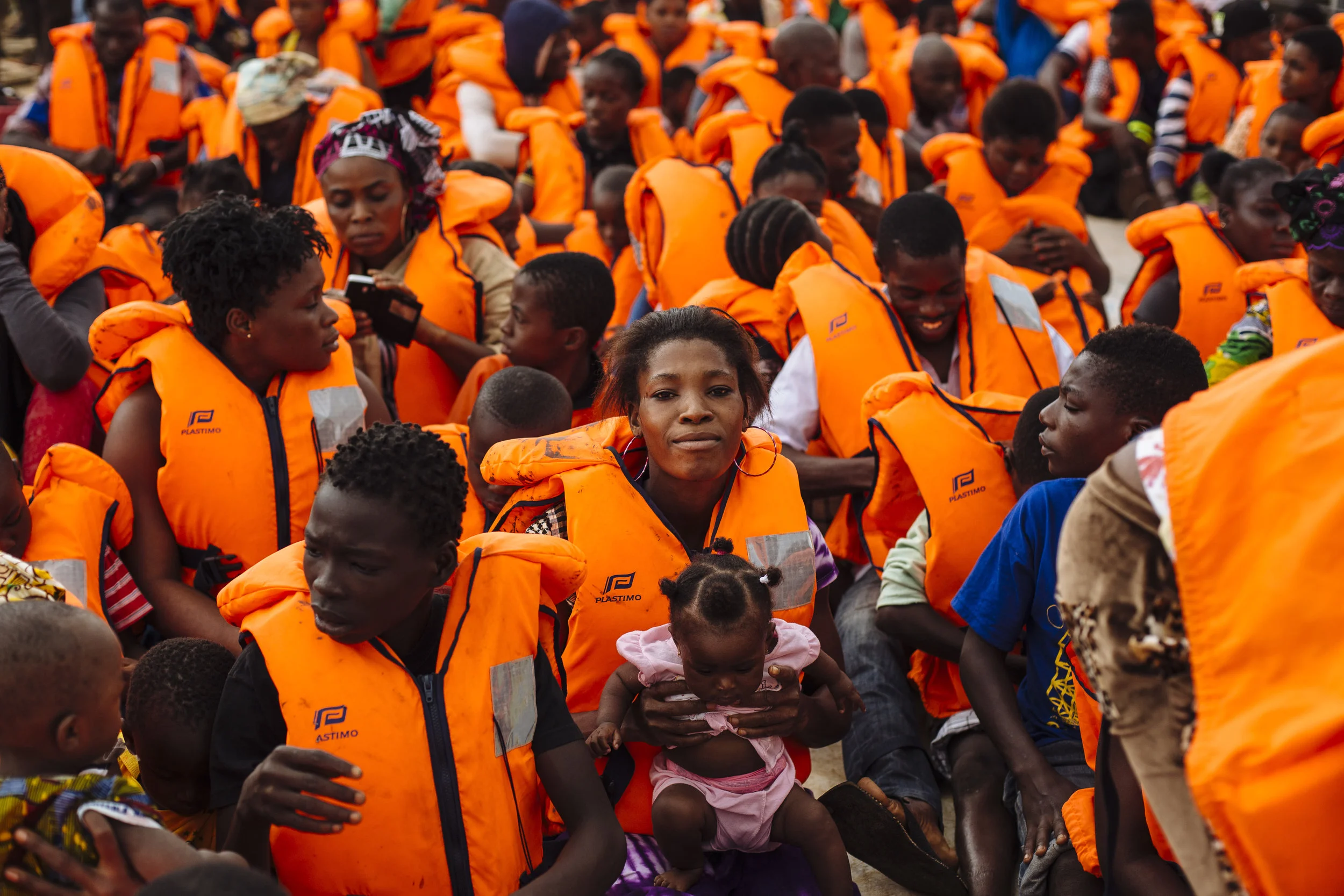Ivorian refugees, wearing safety vests, sit aboard a UNHCR ferry as they are transported across the Cavalla River from Maryland, Liberia to Prollo, Bas-Sassandra District, Côte d'Ivoire.