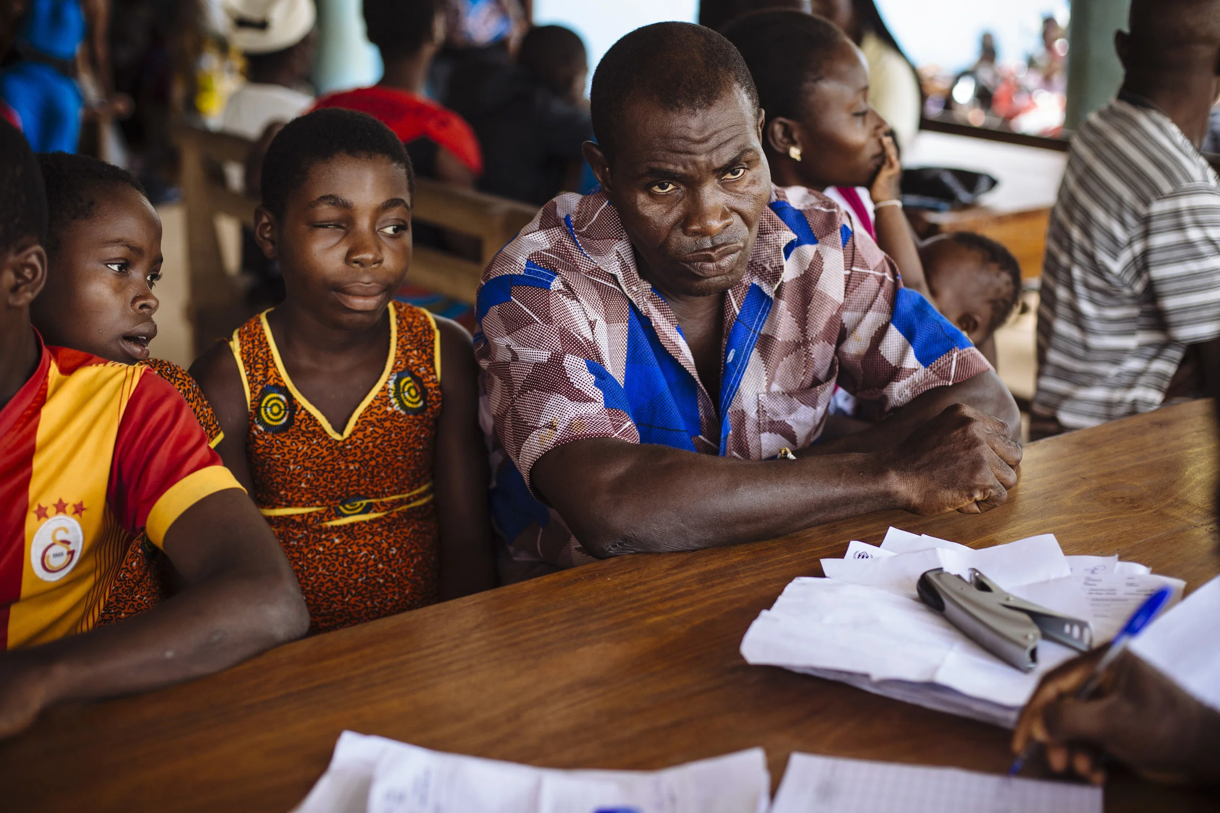 Gbohoun Hie, front right, listens to information provided by ASAPSU (Association de Soutien à l'Autopromotion Sanitaire et Urbaine) along with his daughters Hawae Hie, second from left, and Tahadi Hie, left, at the UNHCR Voluntary Repatriation Transit Center, Tabou, Bas-Sassandra District, Côte d'Ivoire.