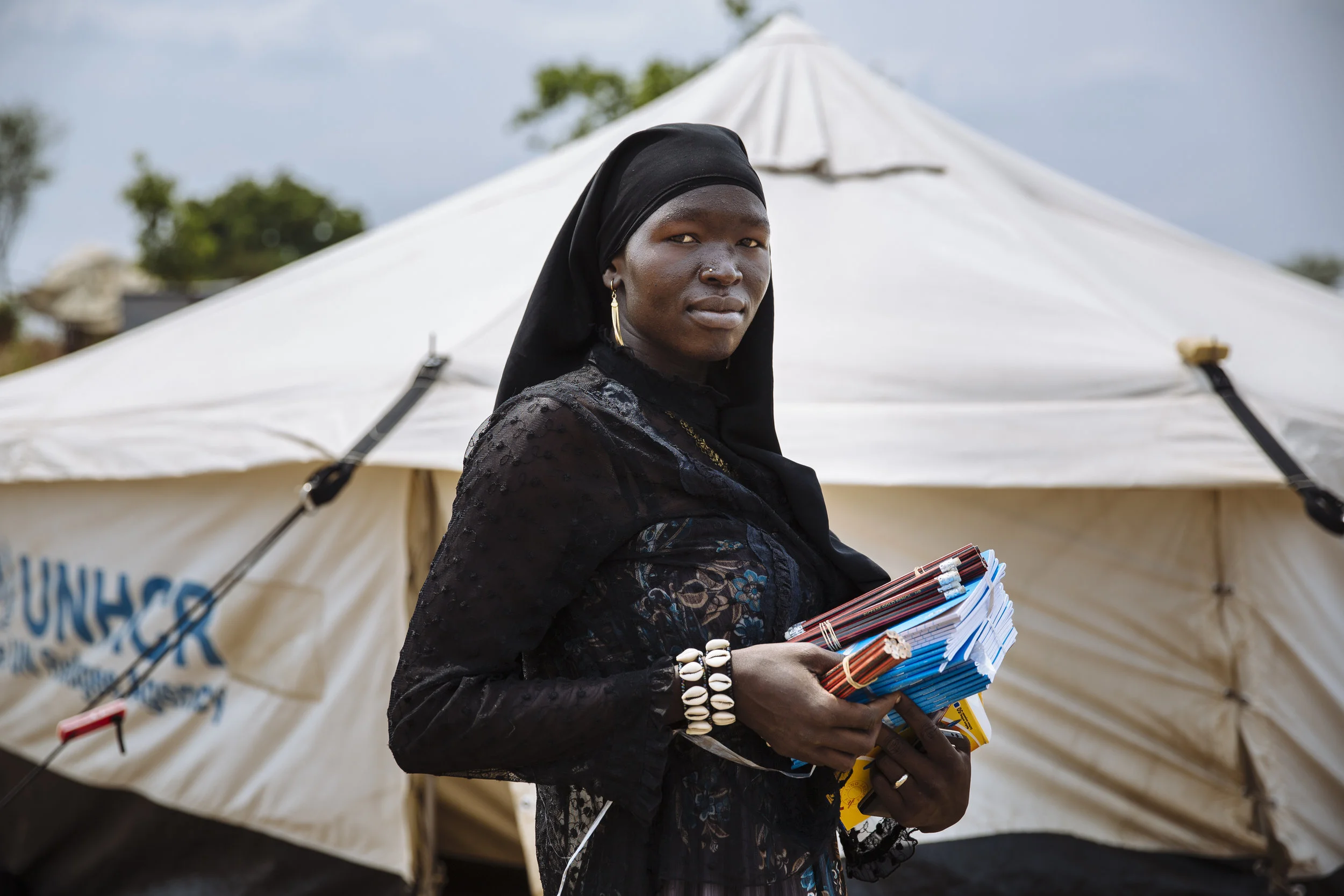 Teacher Bako Zulaika poses for a photograph with teaching supplies outside her shelter at the Ofonze Primary School in Bidibidi settlement, Yumbe District, Northern Region, Uganda.