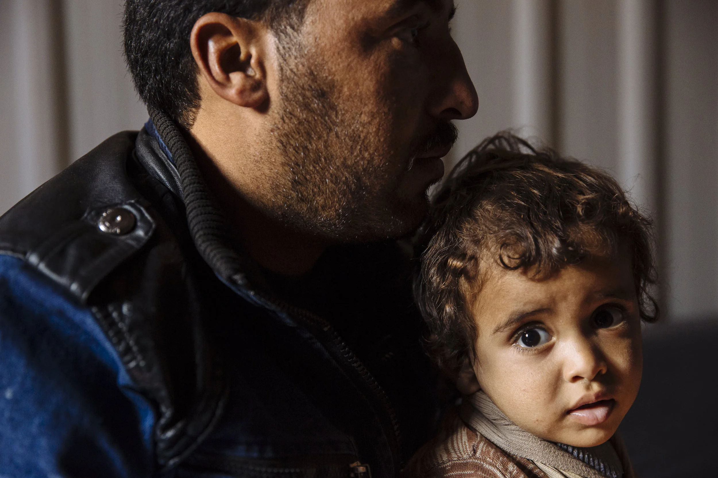 Syrian refugee Khalif, left, sits with his son Hamid during a visit by community health volunteers, in Azraq refugee camp, Zarqa Governorate, Jordan.