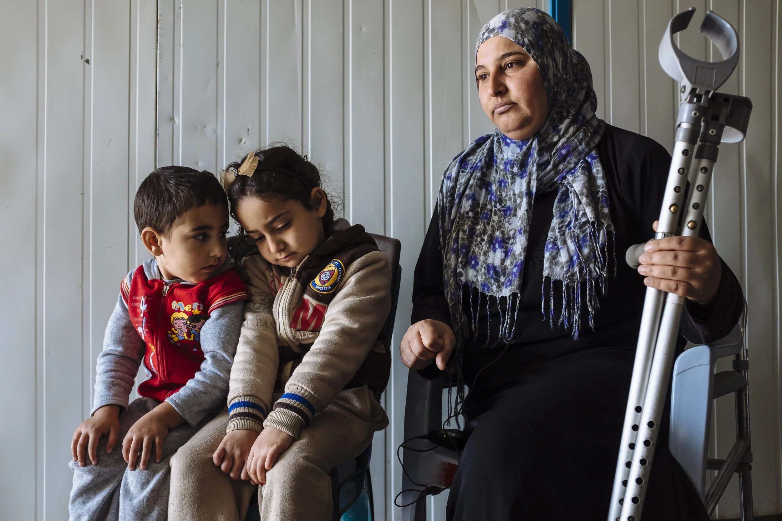 Syrian refugee Hoyada, right, who had her right leg amputated in 2014 after being diagnosed with osteosarcoma (bone cancer), her daughter Bisal, centre, and son Kenan, sit for an interview at their shelter in Za'atari refugee camp, Mafraq Governorate, Jordan.
