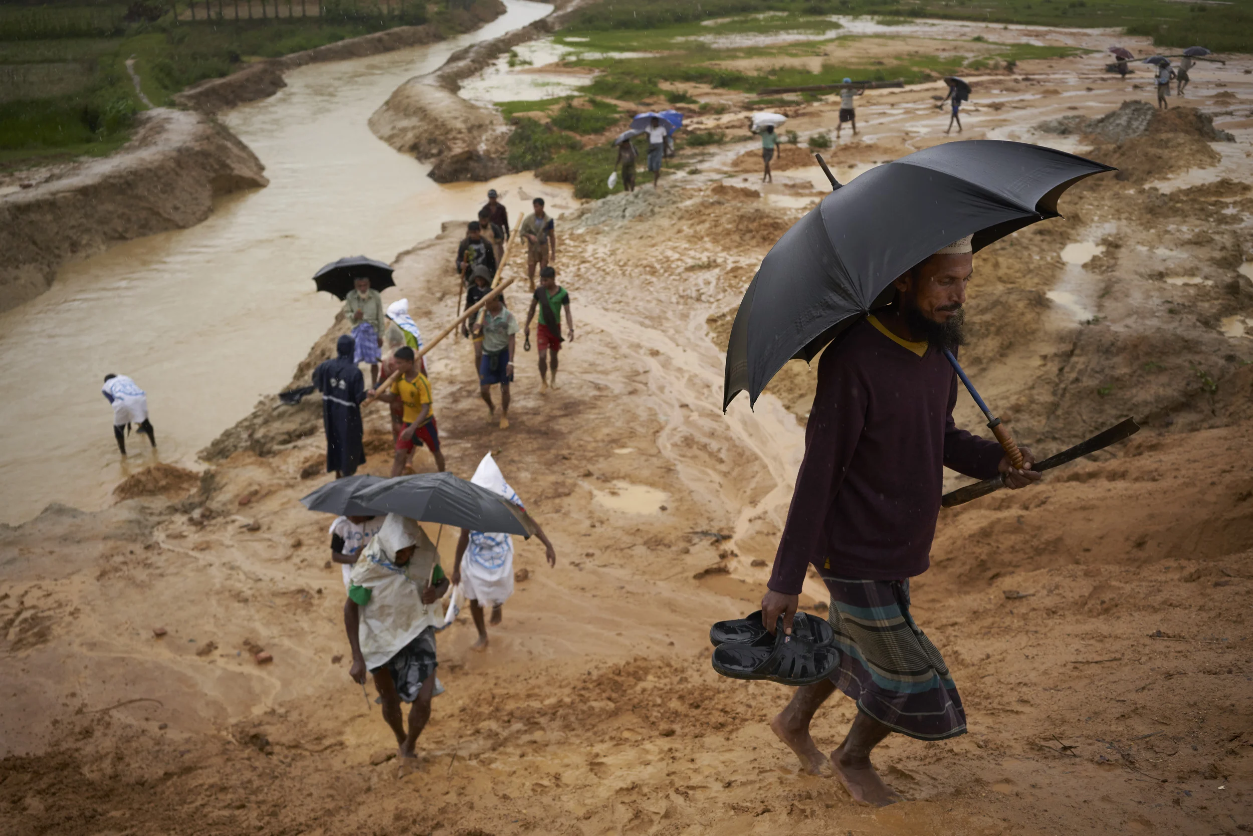 Rohingya refugees walk up an embankment leading to a road undergoing improvement work, in Kutupalong Expansion Site for Rohingya refugees, Ukhia, Cox's Bazar District, Bangladesh.