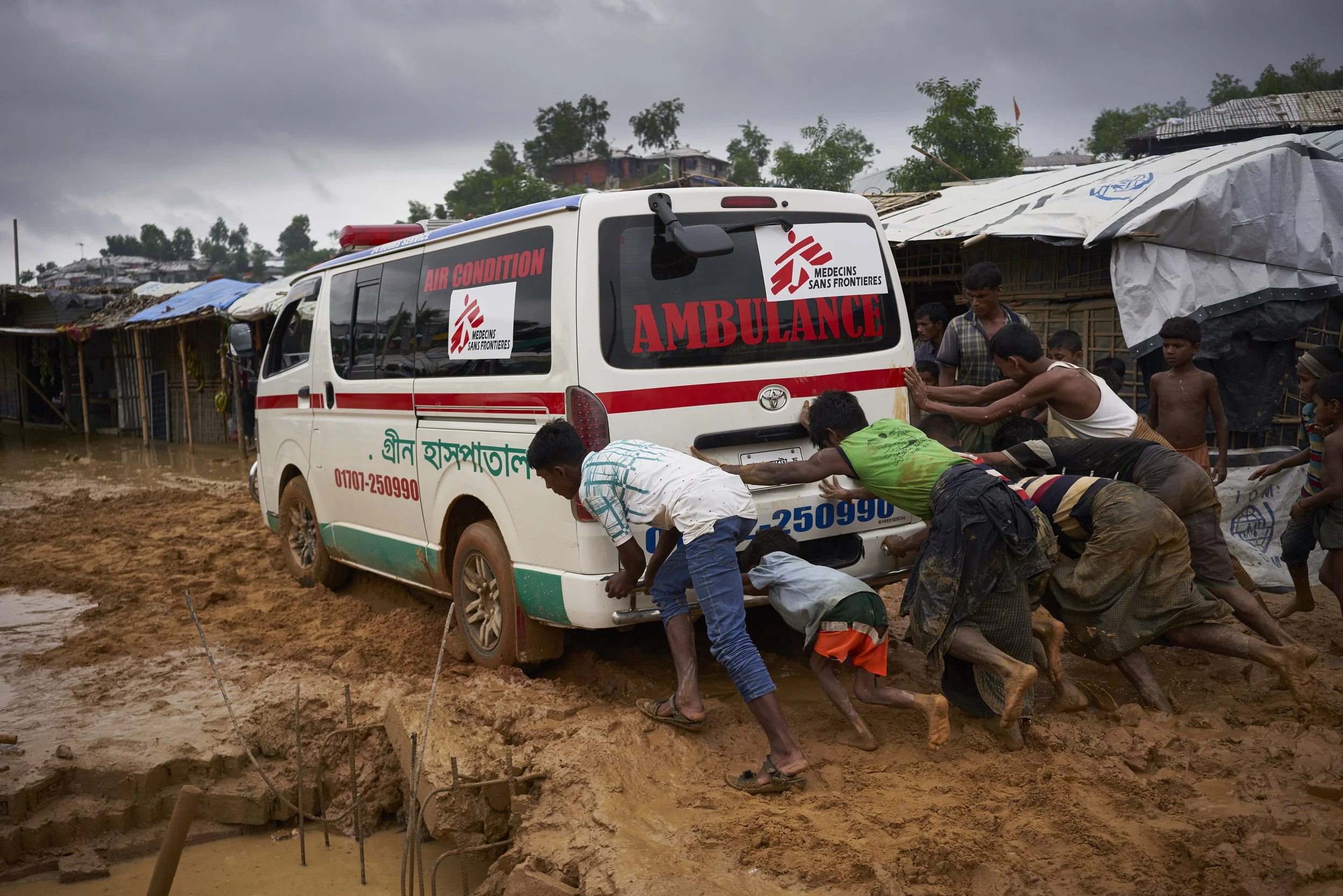 Rohingya refugees help push an ambulance stuck on a road damaged by heavy monsoon rains in Kutupalong Expansion Site for Rohingya refugees, Ukhia, Cox's Bazar District, Bangladesh.