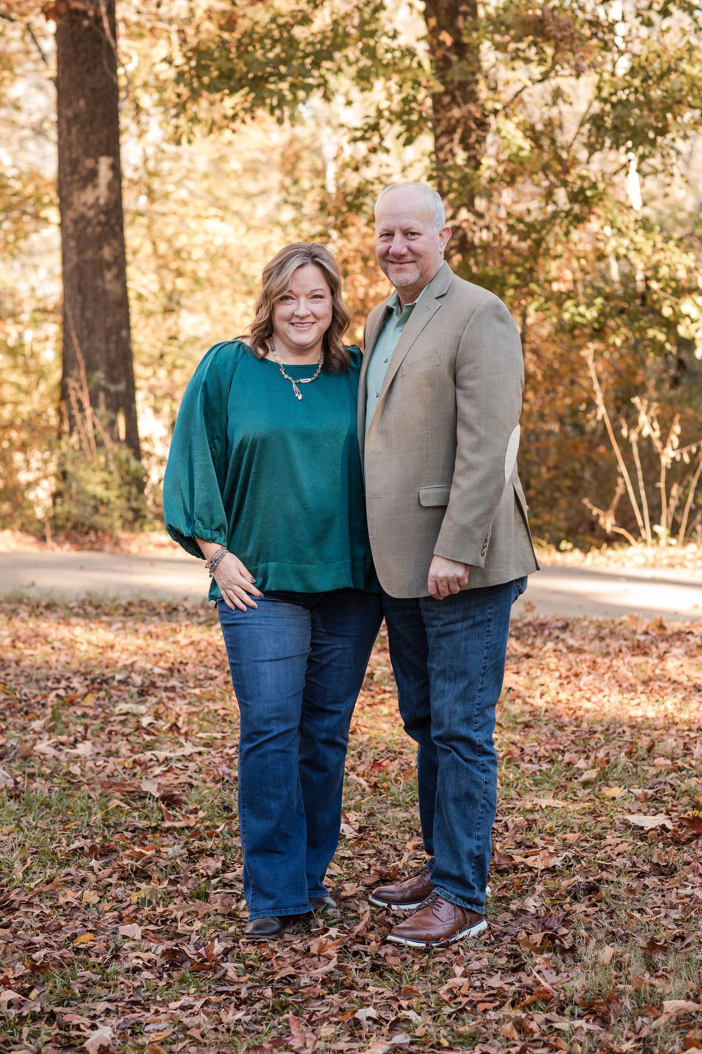 Couple standing in trees in fall