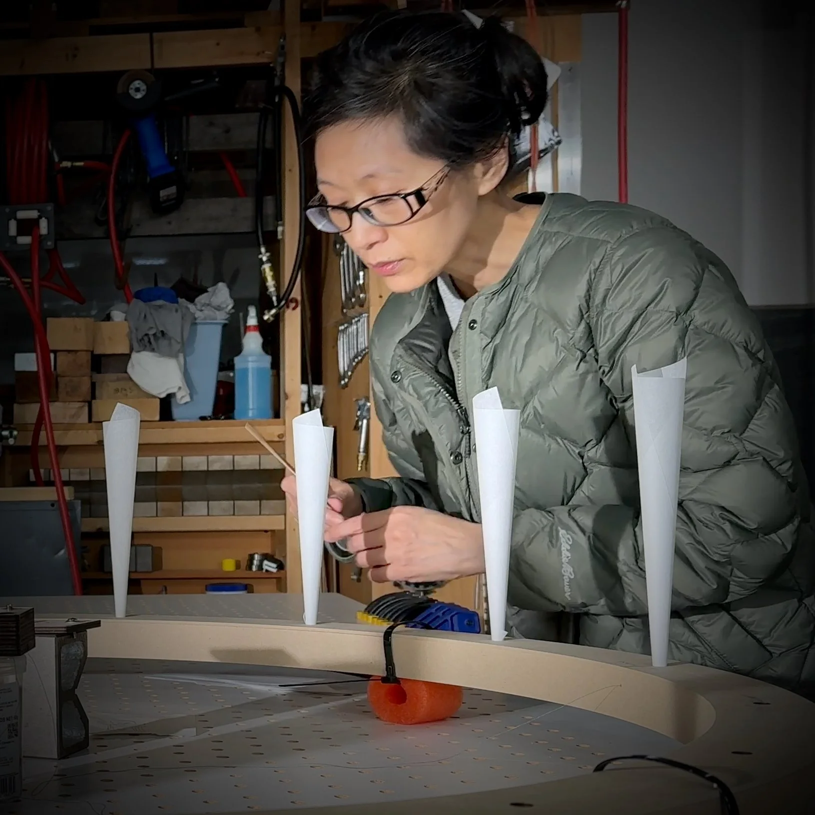 A portrait of artist Wan-Yi Lin from Mizzonk working in their studio, particularly on a chanderlier from their installation H O M E ≠ H•O•M•E