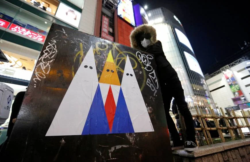 A graffiti artist known as 281_Anti Nuke poses for a photo next to an example of his recent artwork depicting U.S. President Donald Trump, in Tokyo's Shibuya district on Friday.