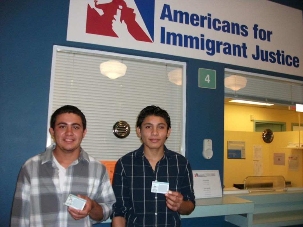 Brothers who arrived as unaccompanied minors smile as they receive their green cards.