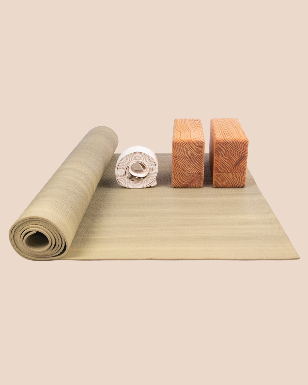 wooden colored yoga blocks, rolled up white yoga strap and light brown colored yoga mat partially rolled.
