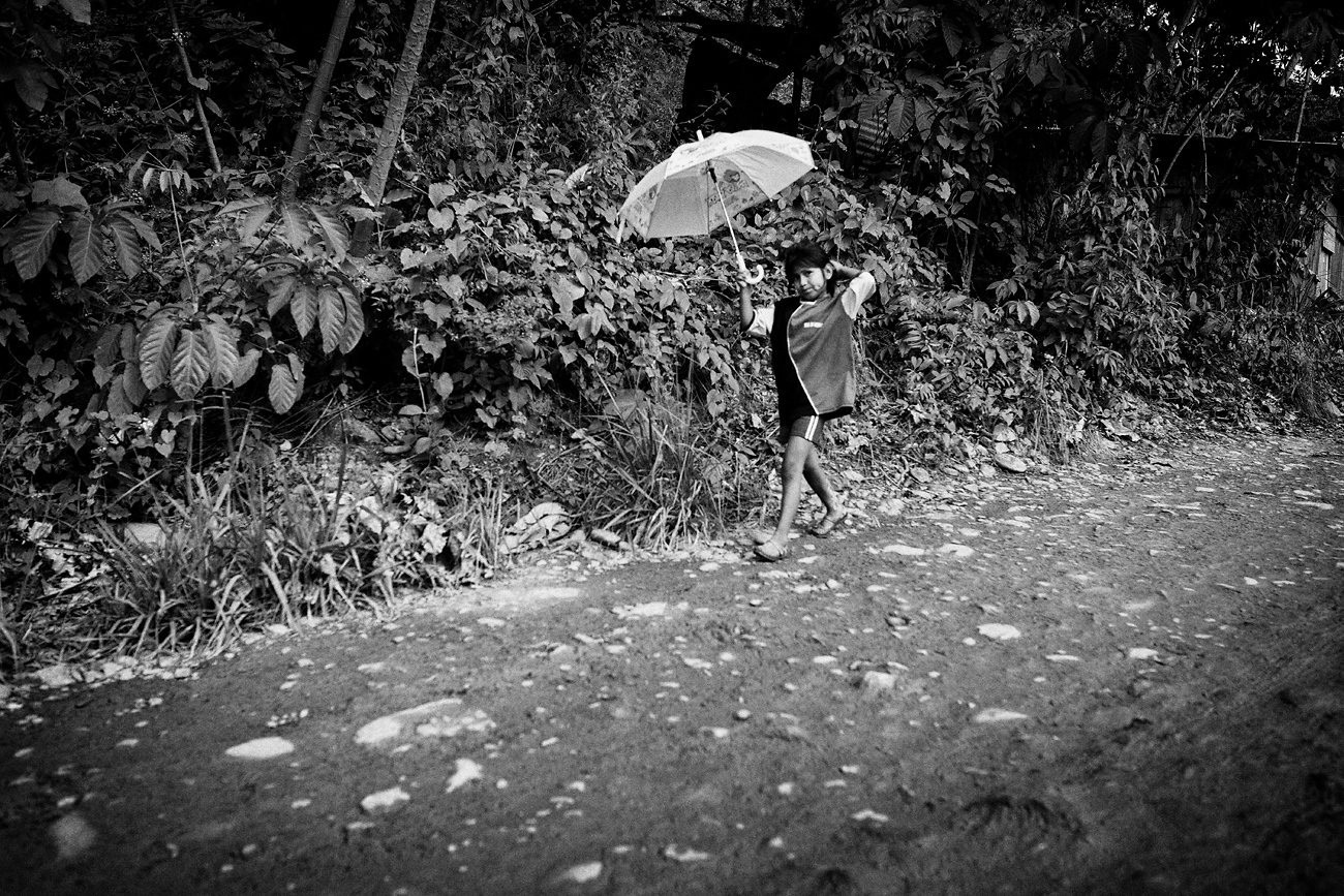 young girl protects herself from the sun with an umbrella. Tipuani, Bolivia.  