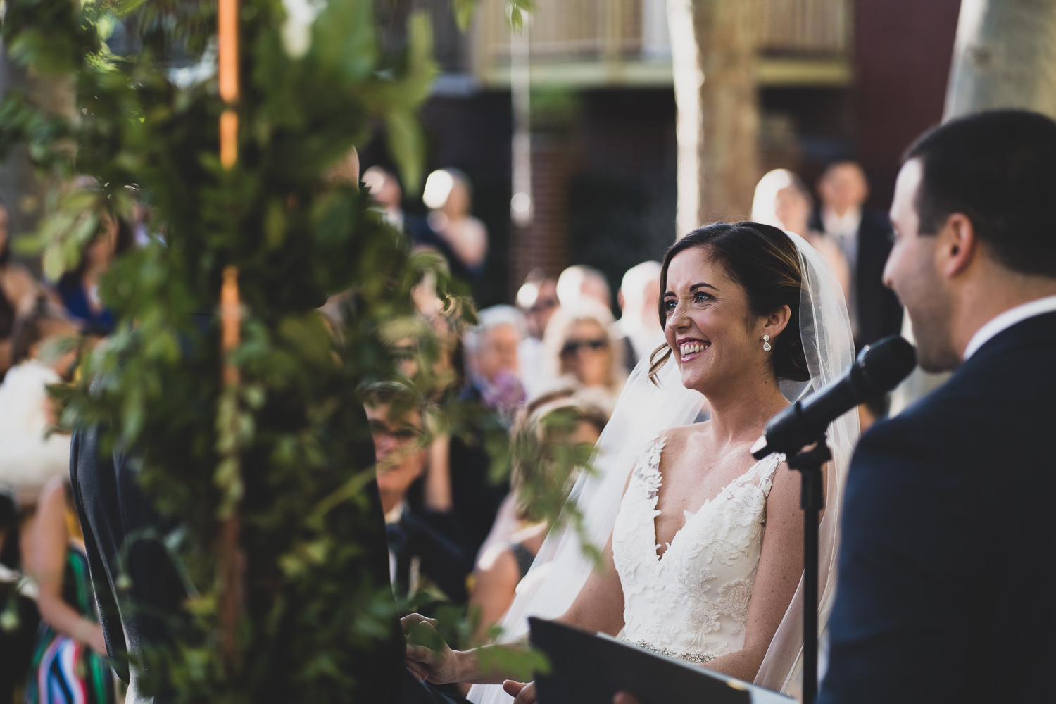 Bride smiles at her soon to be husband during ceremony at Fleisher Art Museum